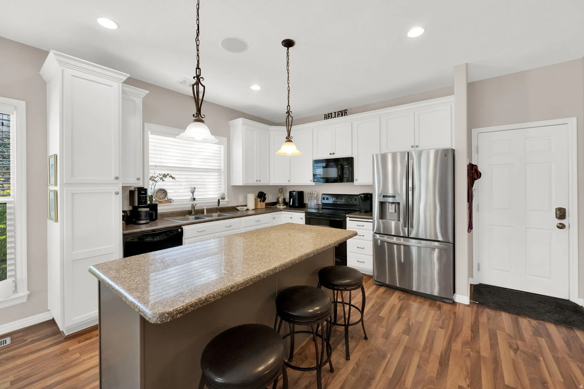 Kitchen featuring a central island with a stone-finish countertop, white cabinetry, wood-finish flooring, and recessed lighting
