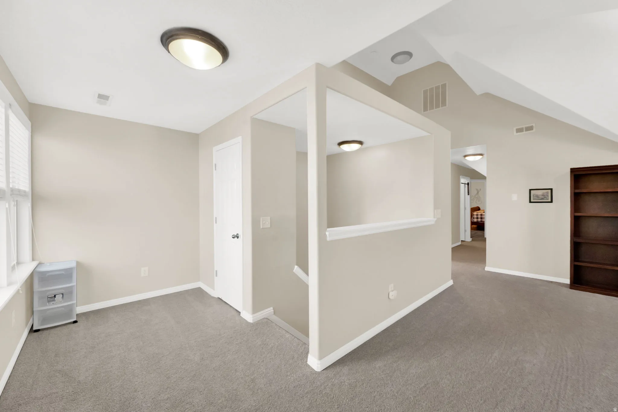 Versatile upper-level area featuring neutral carpeting, light-toned walls, and a window with blinds