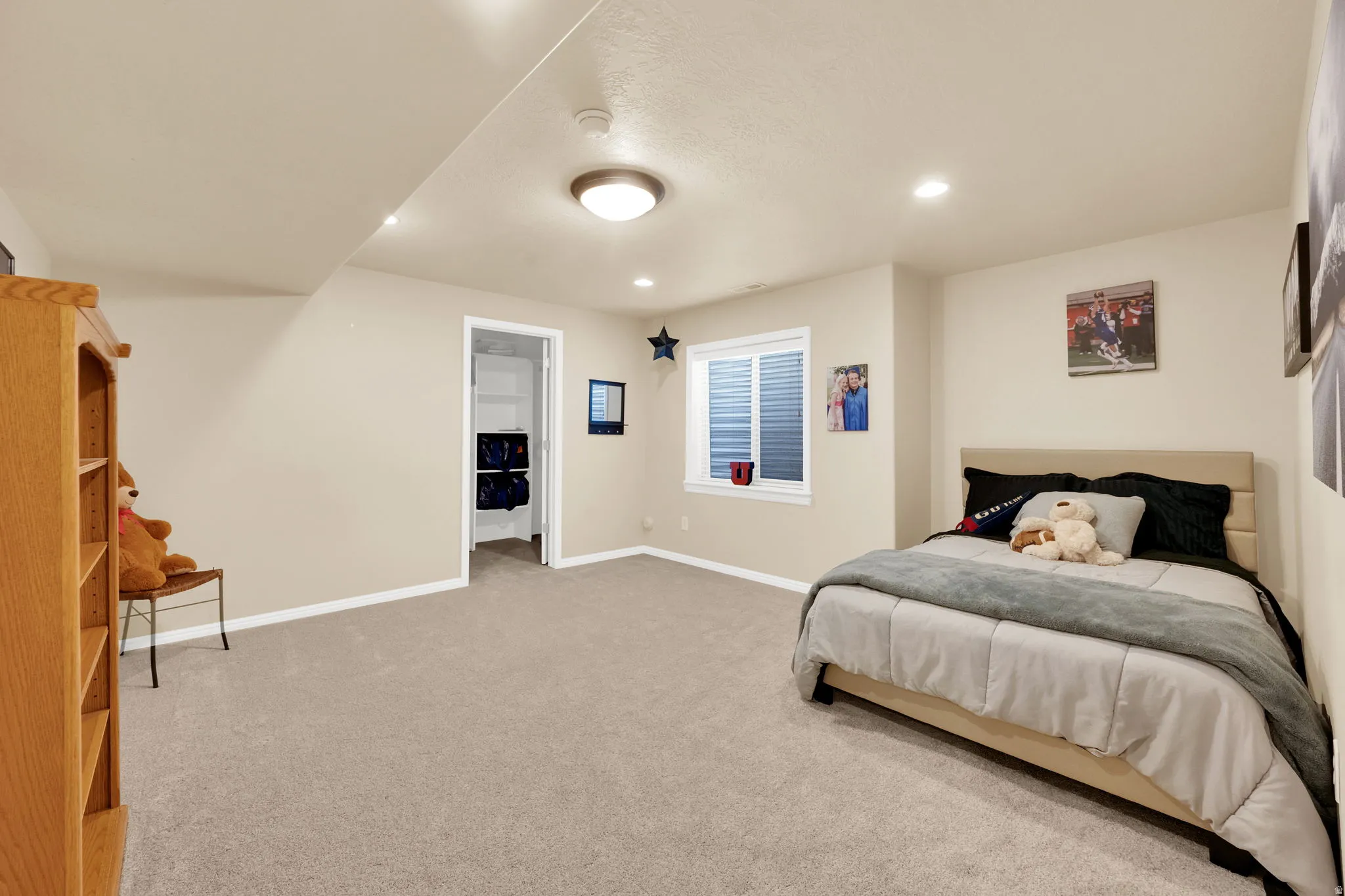 Carpeted room featuring neutral wall tones, recessed lighting, a window with horizontal blinds, and a doorway opening to a closet