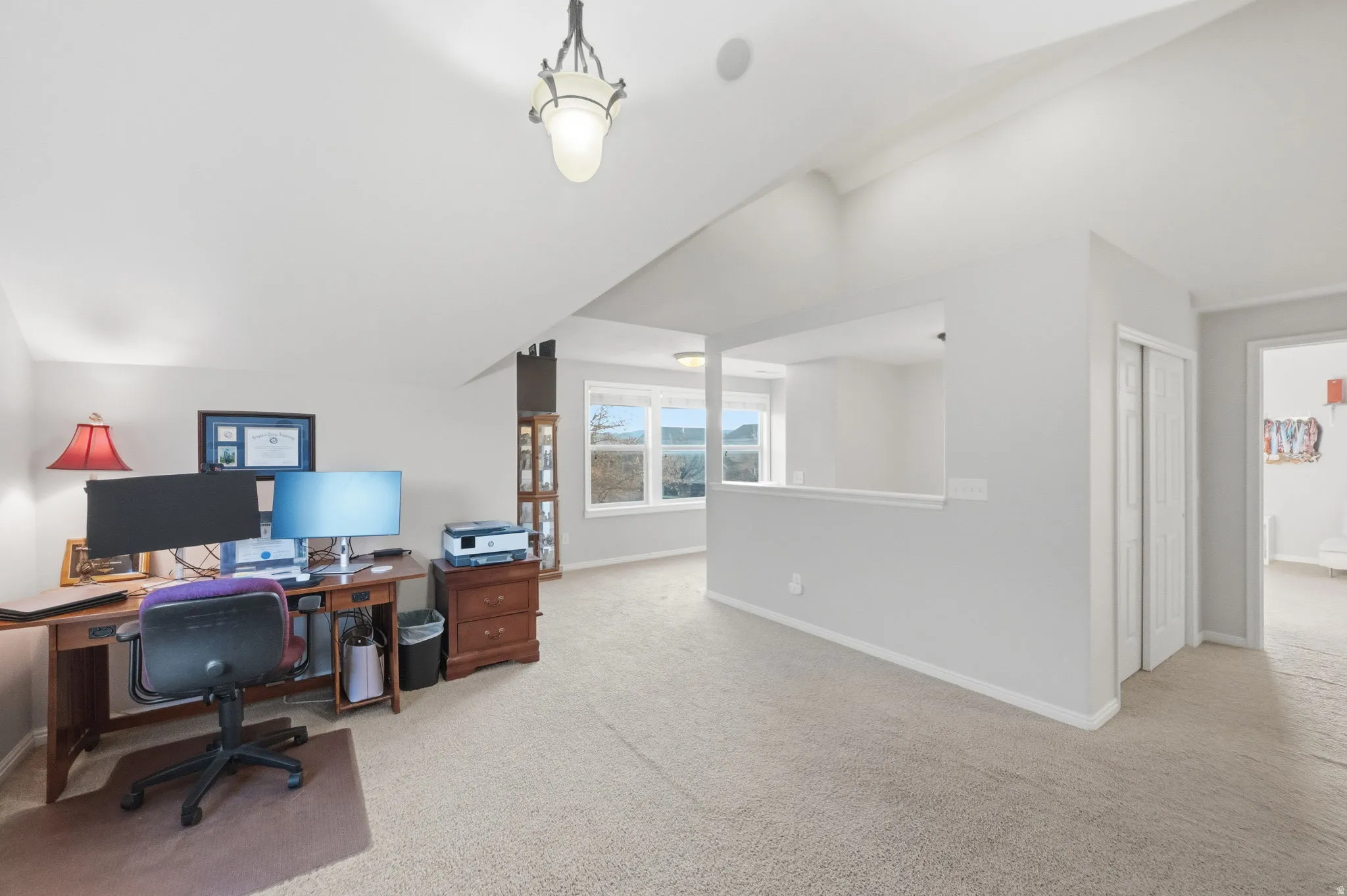 Expansive loft area featuring vaulted ceilings, neutral carpeting, and a built-in half-wall partition