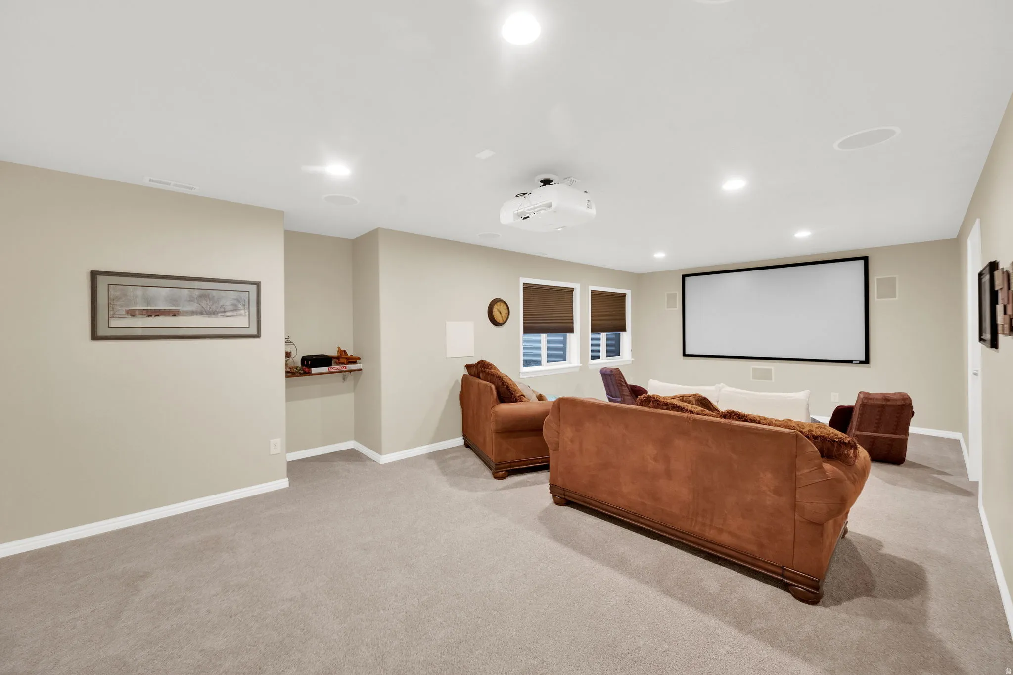Dedicated media room featuring a large projection screen, mounted projector, recessed lighting, and integrated ceiling speakers