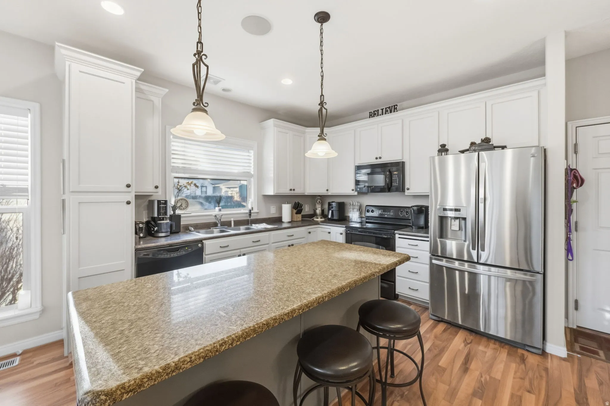 Kitchen featuring white cabinetry, stone-finish countertops, stainless steel appliances, and wood-finish flooring