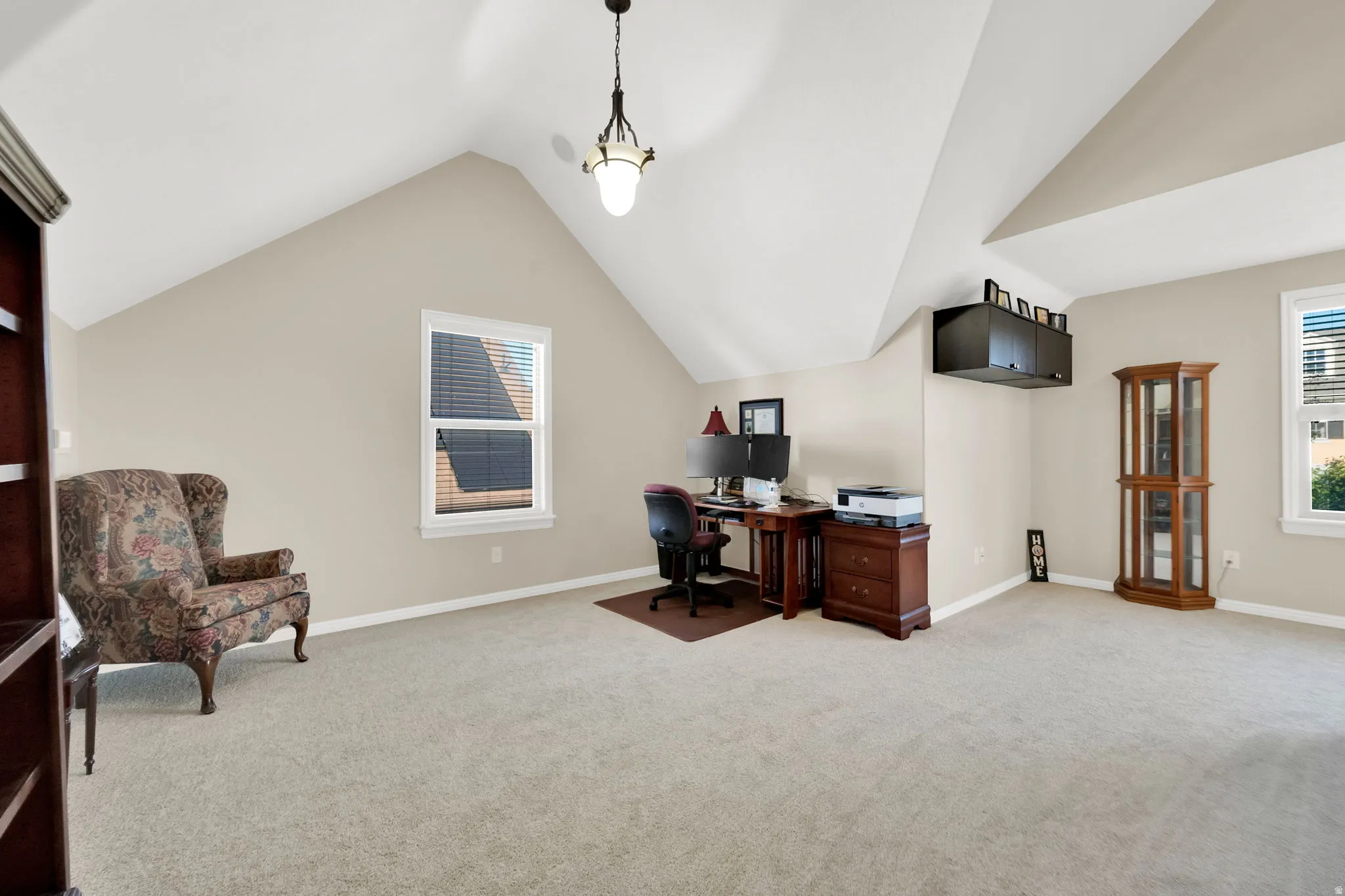 Spacious room with a vaulted ceiling, recessed window, and light-toned carpeting