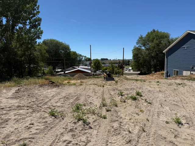 Expansive land parcel featuring a gentle slope, minimal existing vegetation, and a clear blue sky overhead