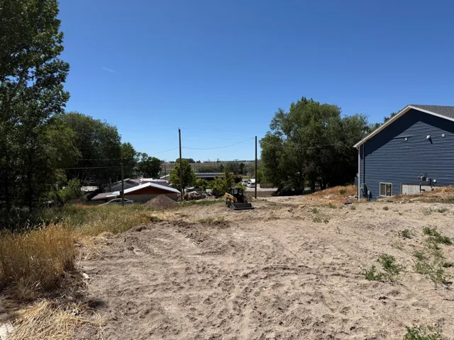 Cleared lot with visible groundwork and a portion of a blue-sided structure