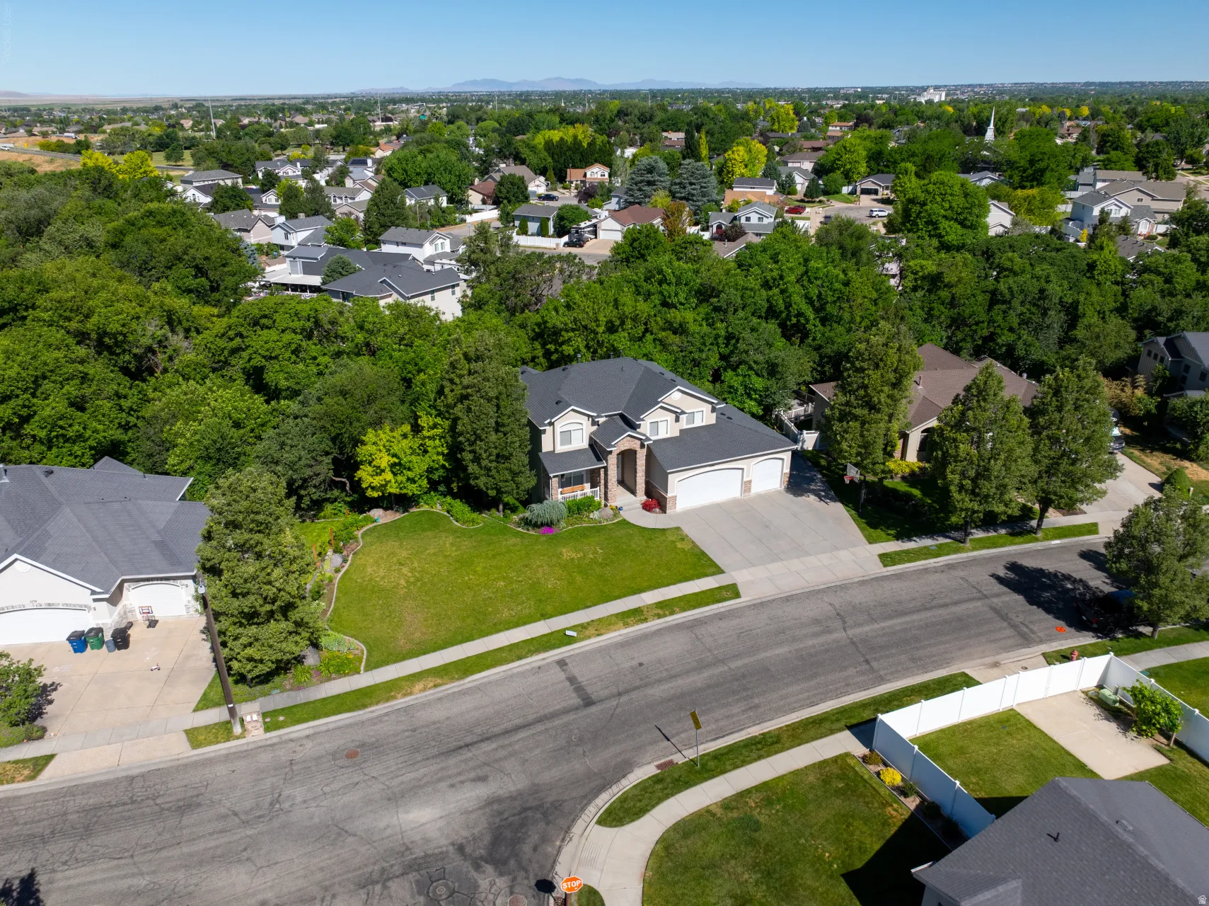Traditional-style residence with a two-car garage, established landscaping, a paved driveway, and a front lawn