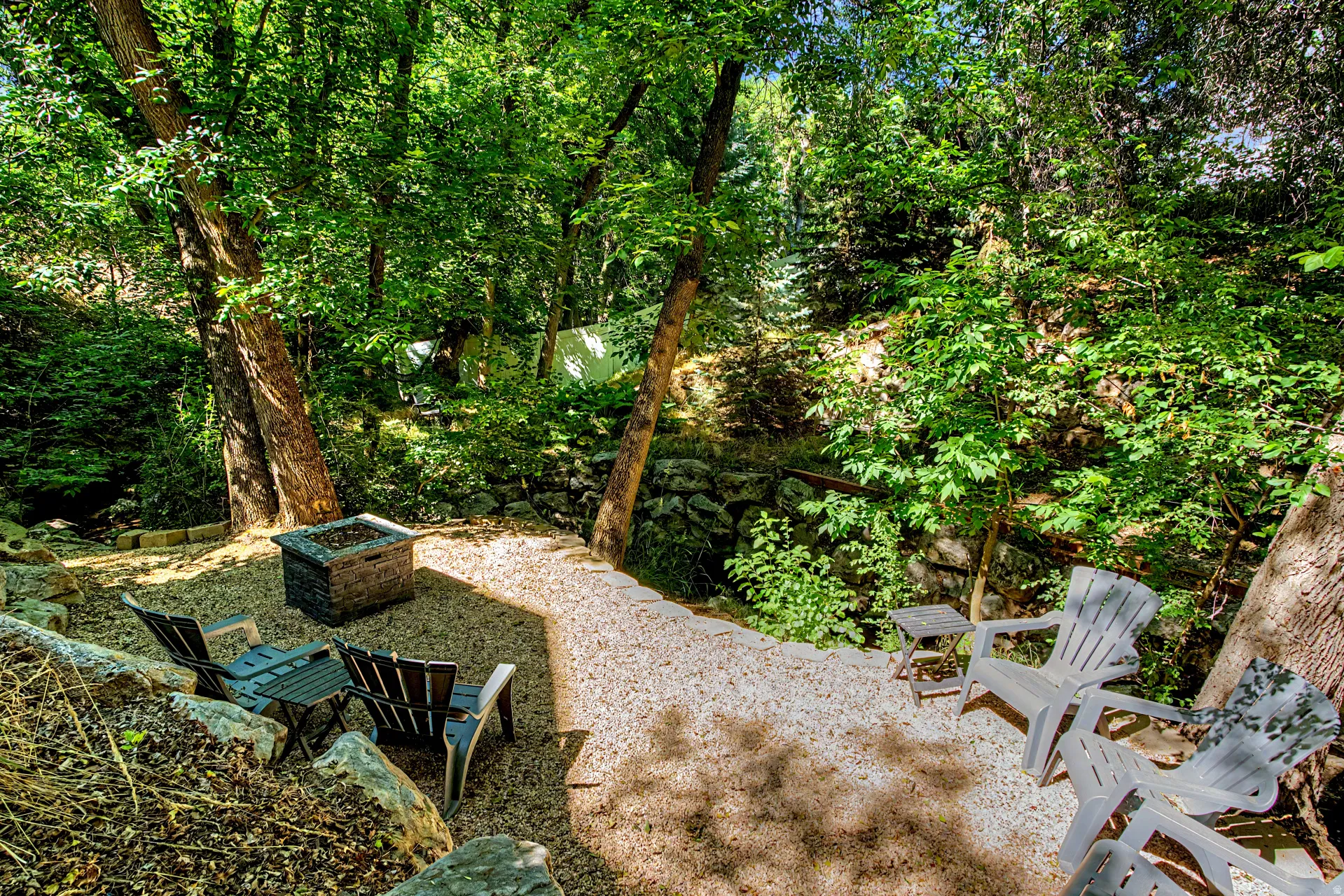 Terraced outdoor area featuring gravel ground cover and a stone fire pit