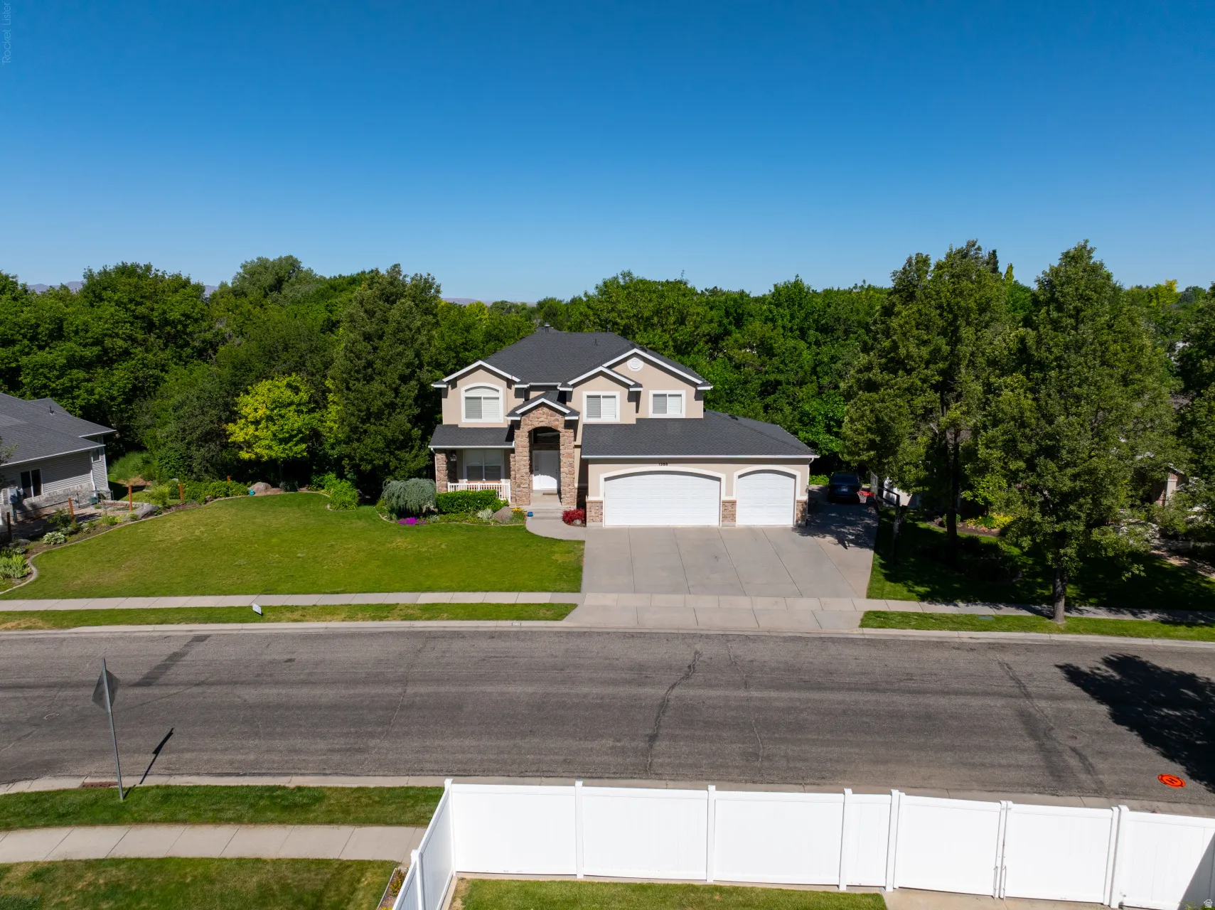 Two-story residence featuring a stone and stucco exterior, a dark shingle roof, and a three-car garage