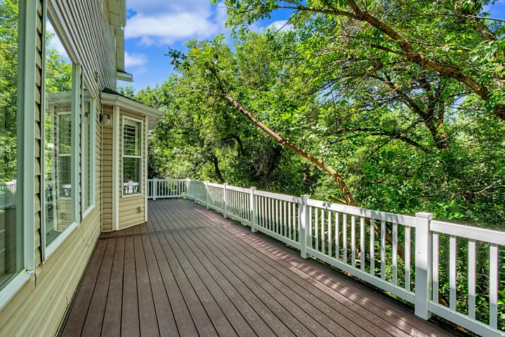 Expansive outdoor deck featuring composite decking, white railing, and exterior wall lighting