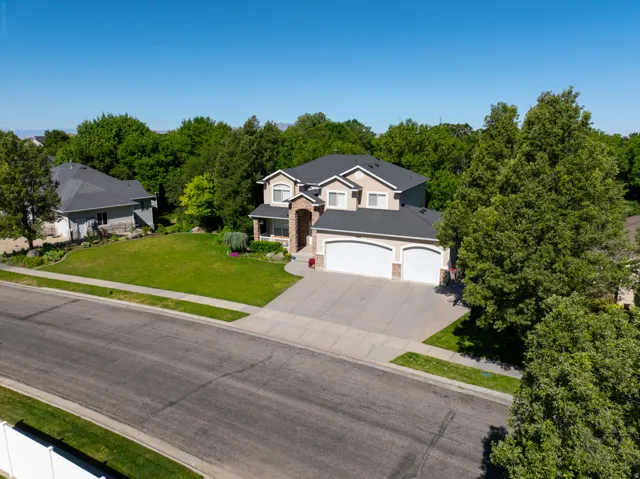 Two-story property featuring a tan stucco and brick facade with a prominent two-car garage