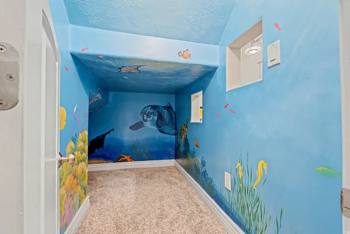 Interior room featuring custom underwater-themed wall and ceiling murals, light-toned carpeting, and white baseboards