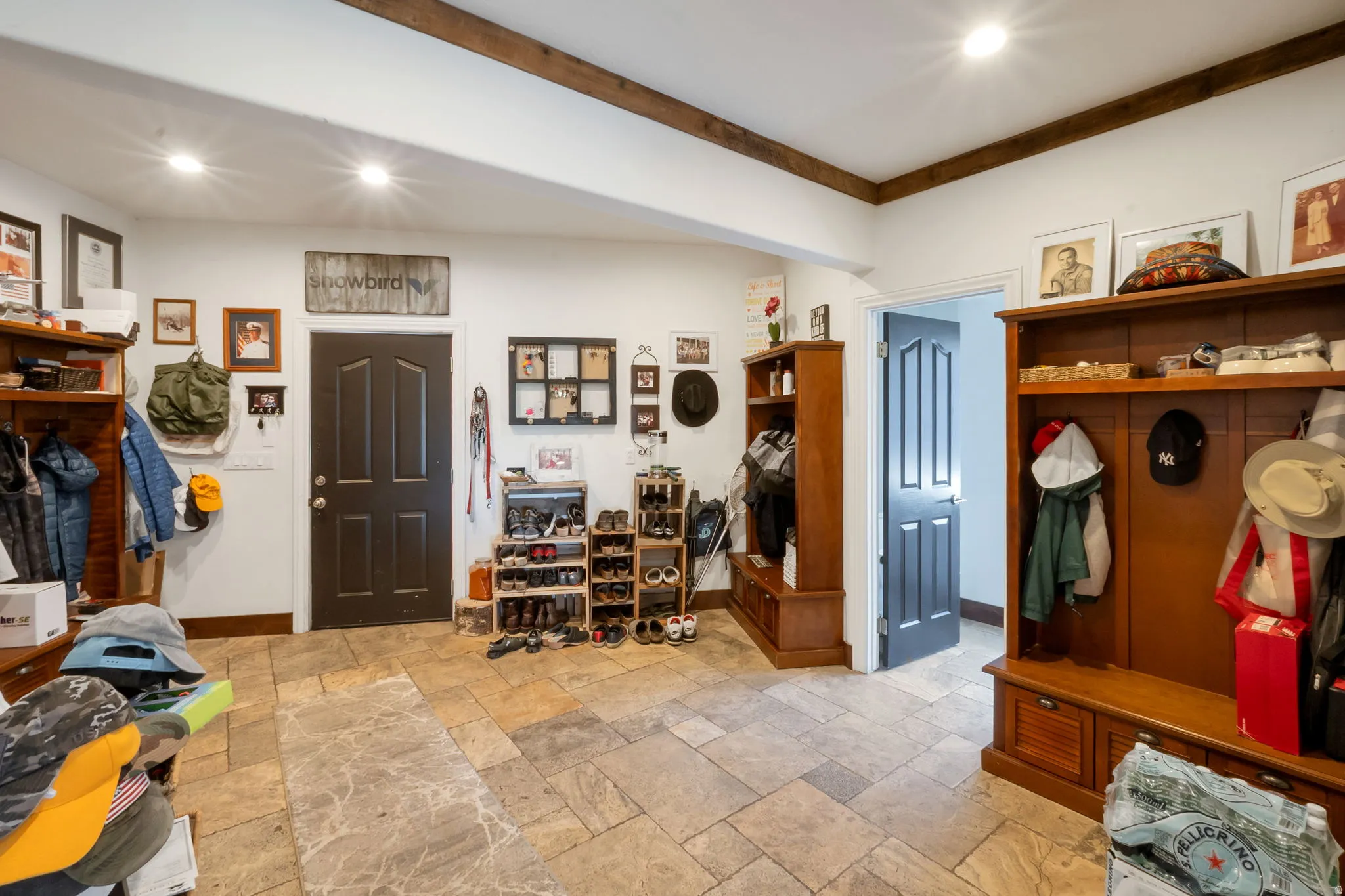 Entry area featuring broad tile flooring with varied tones, exposed wood beams, and recessed lighting
