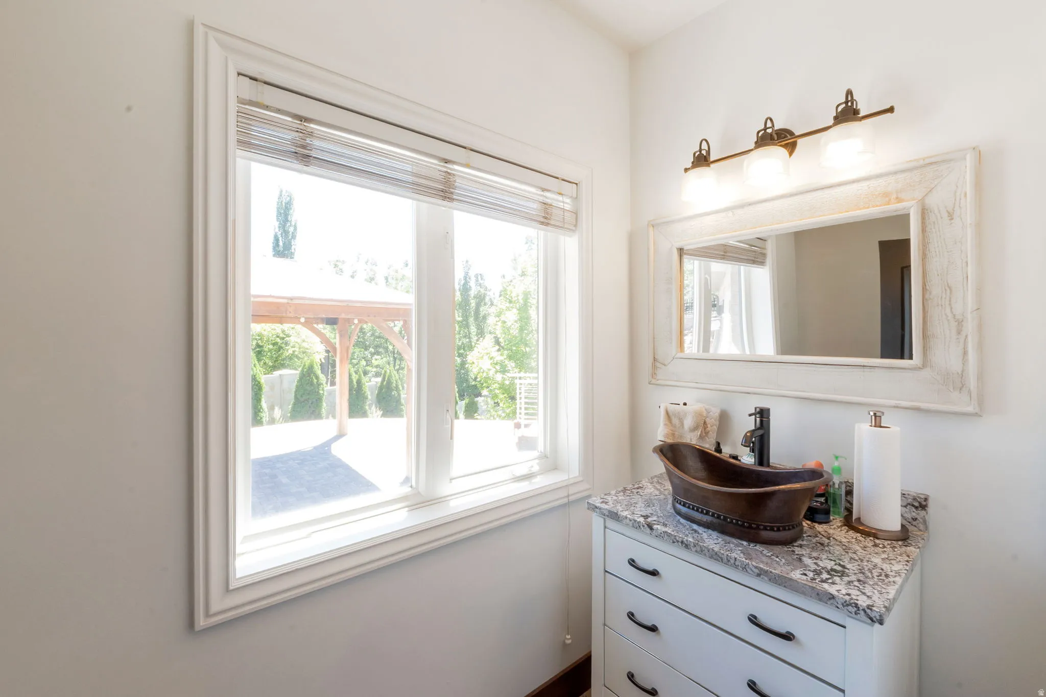 Guest Bathroom - Vanity featuring a vessel sink, stone countertop, and white cabinetry with dark hardware