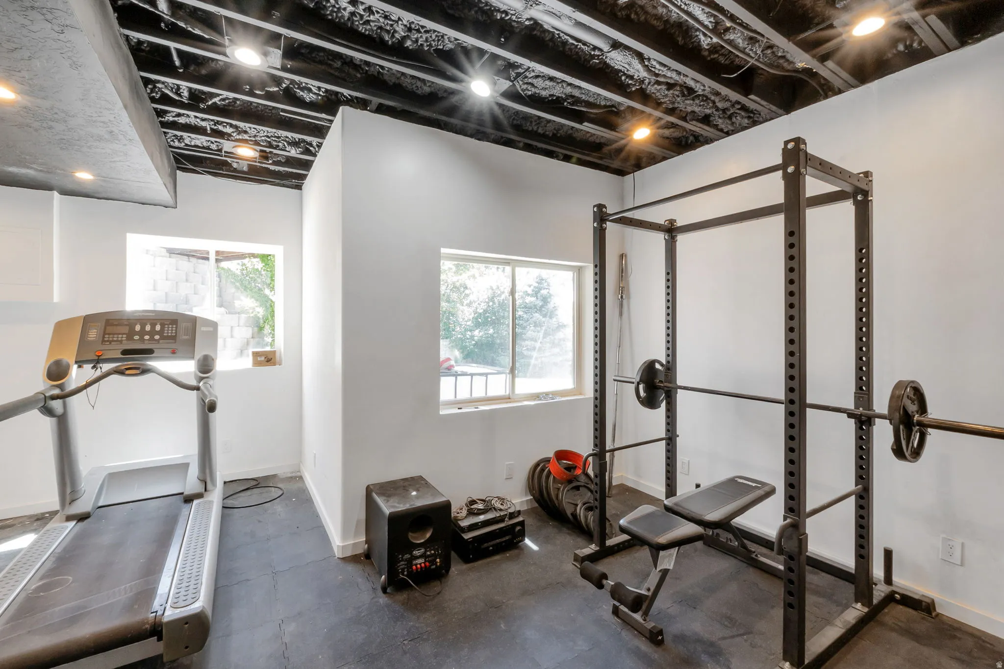 Dedicated fitness space featuring a black exposed ceiling with recessed lighting