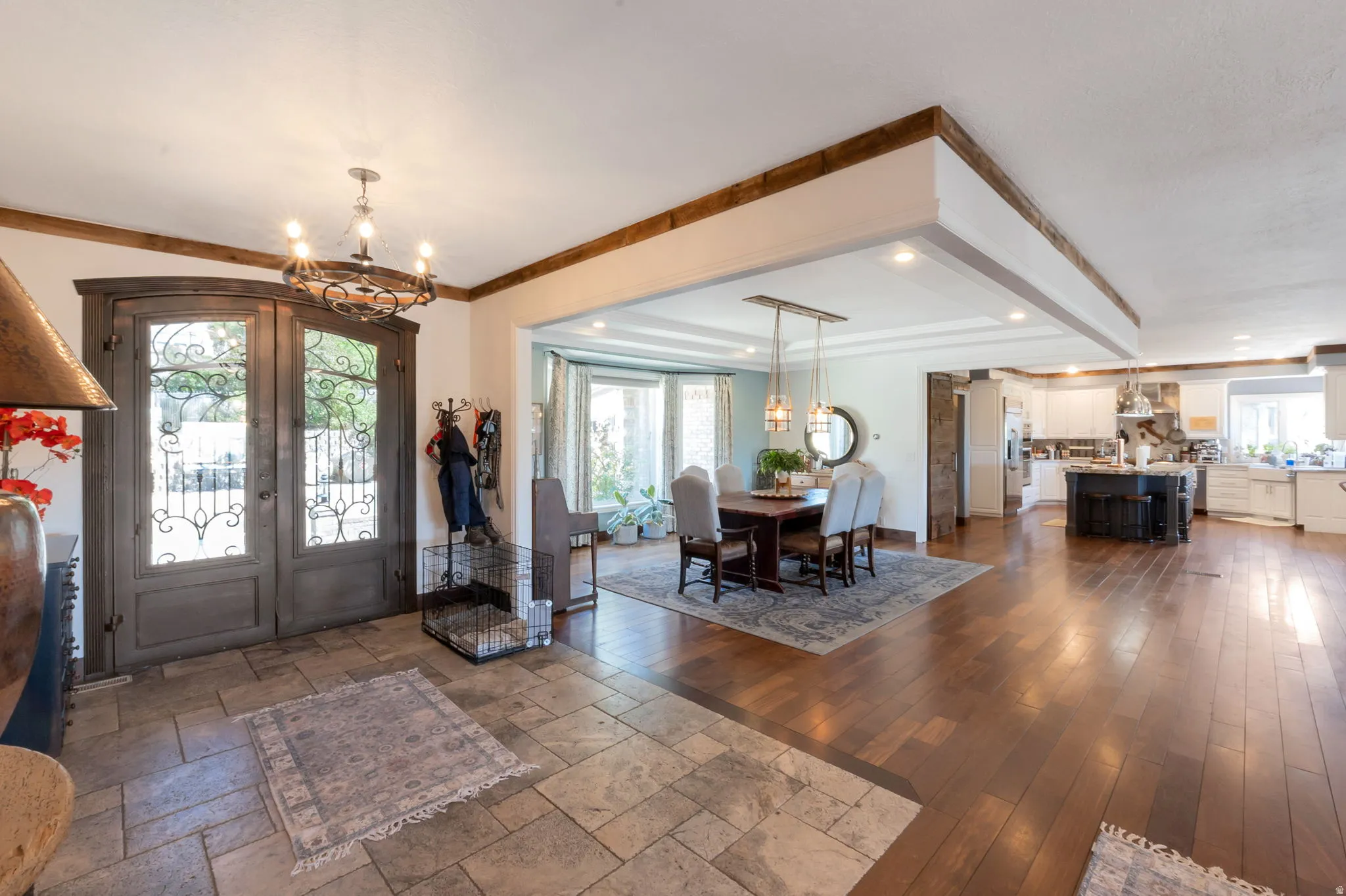 Entryway featuring double wood doors with decorative ironwork, a wrought iron chandelier, and stone-finish flooring