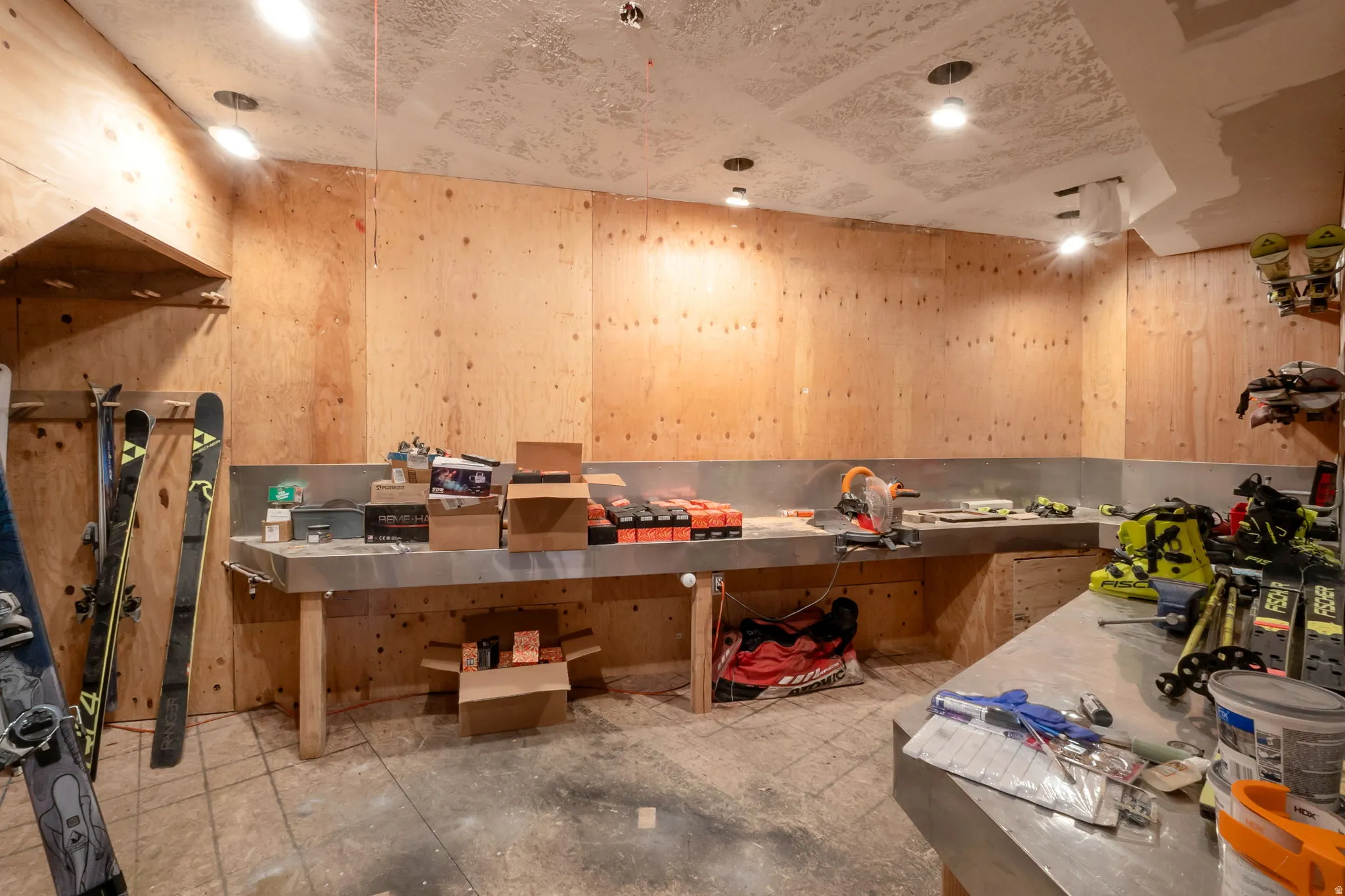 Utility space featuring plywood paneling, built-in metal countertops, recessed lighting, and a durable flooring surface