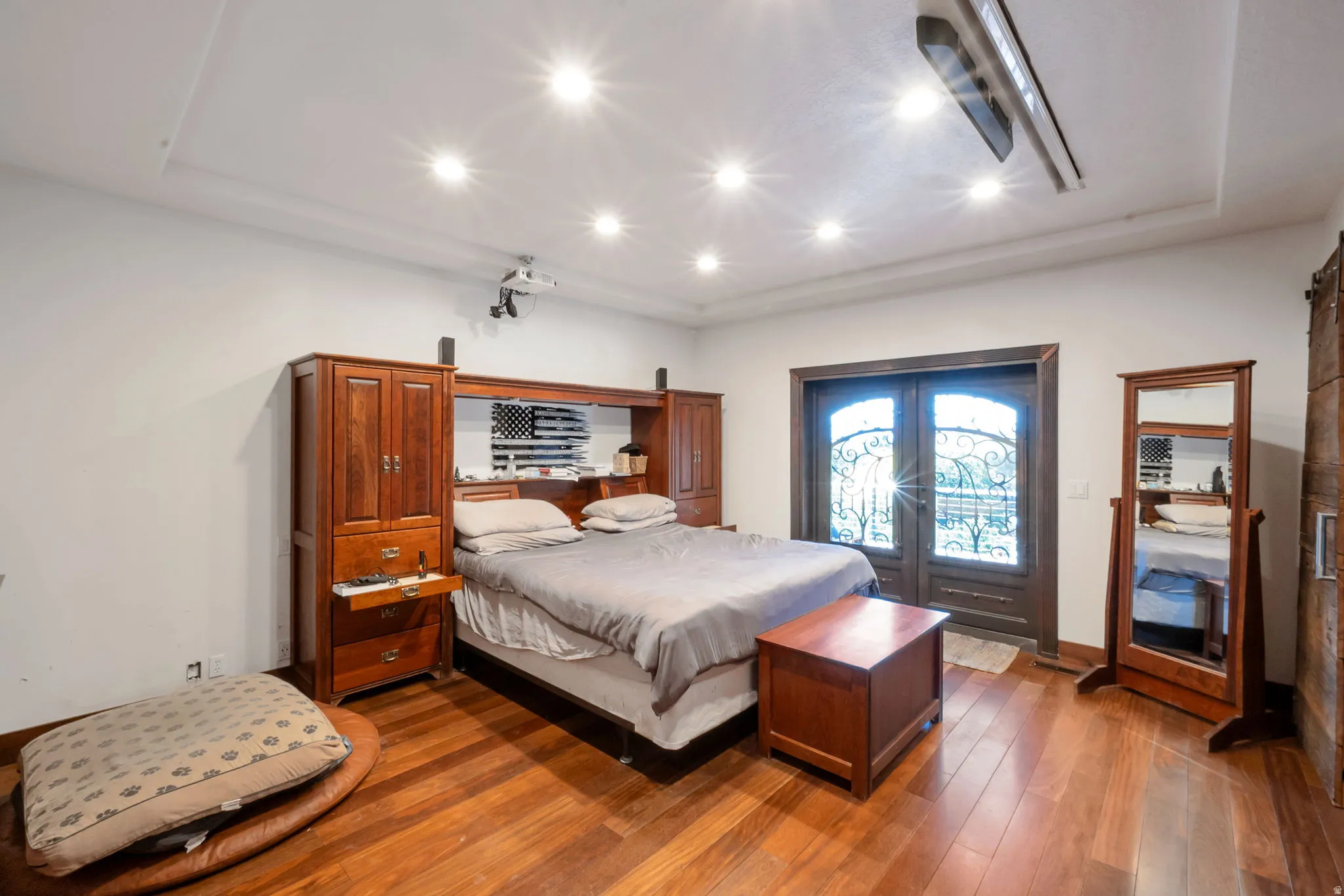 Hardwood flooring throughout featuring recessed ceiling lighting, a built-in drop down projector screen, with Projector, and double arched doors with decorative wrought iron detailing
