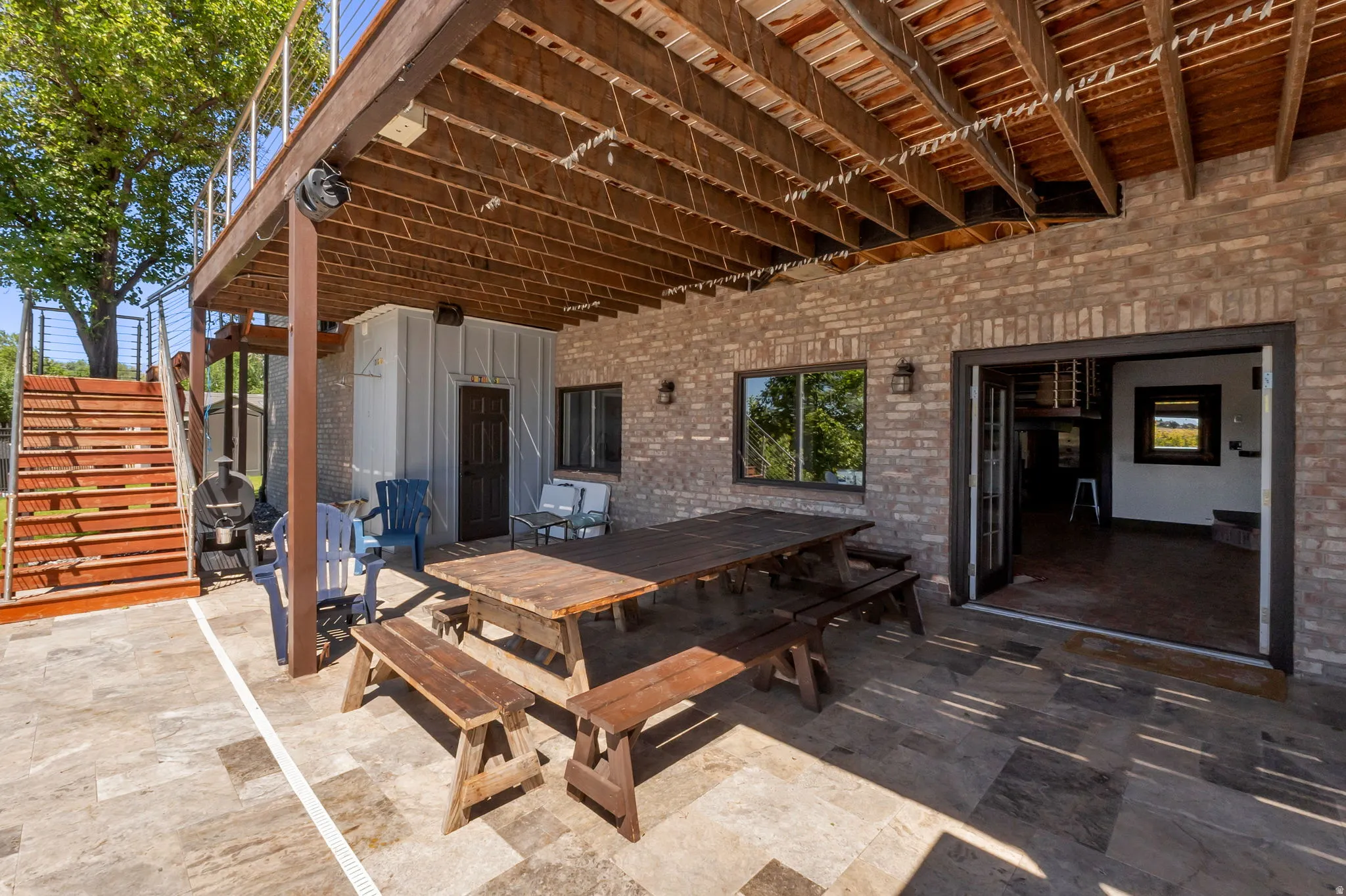 Ground-level patio featuring brick construction, a covered wood-beam ceiling, and a full-light double door entry