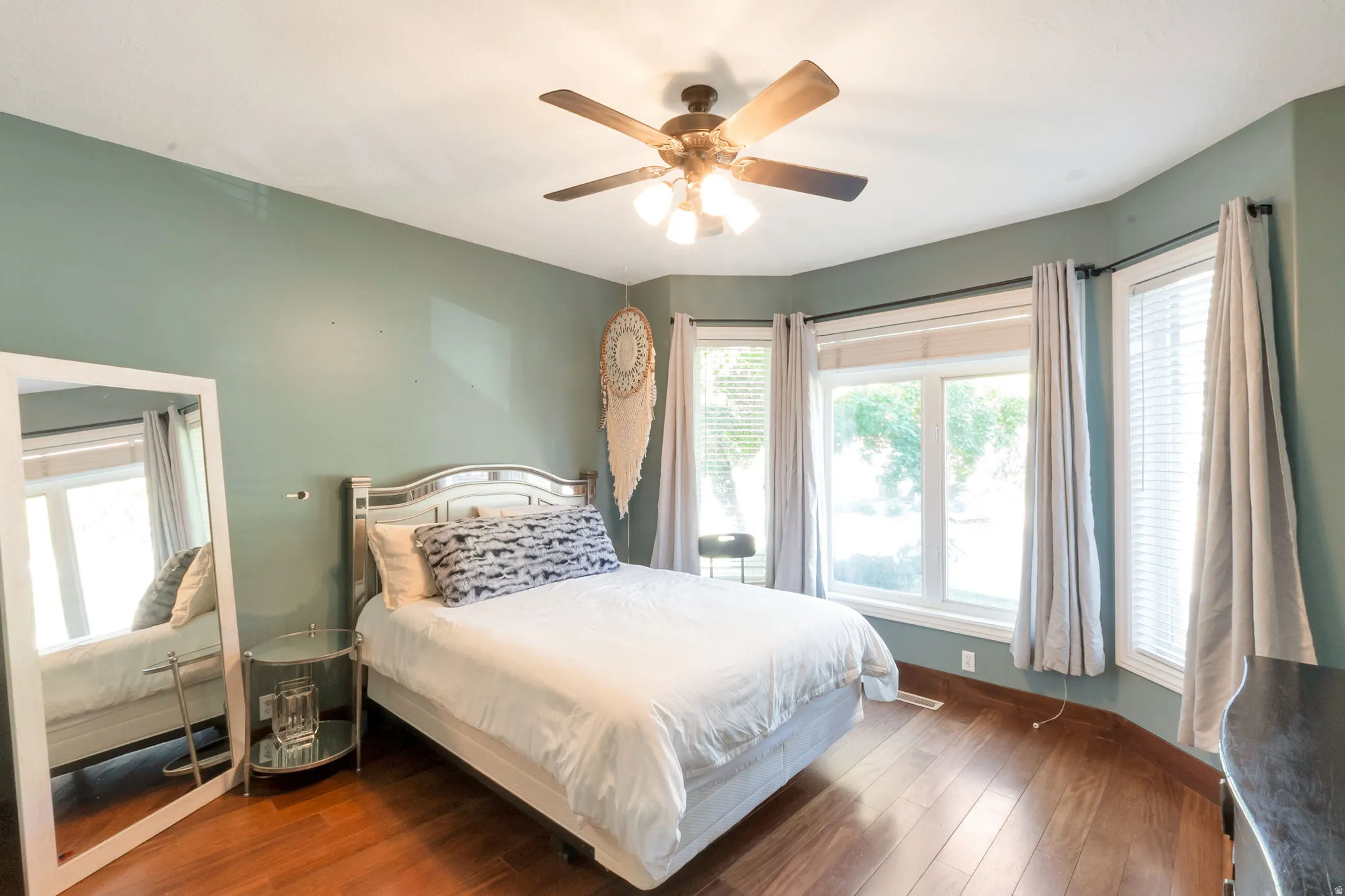 Room featuring wood-finish flooring, a multi-window bay, and a ceiling fan with integrated lighting
