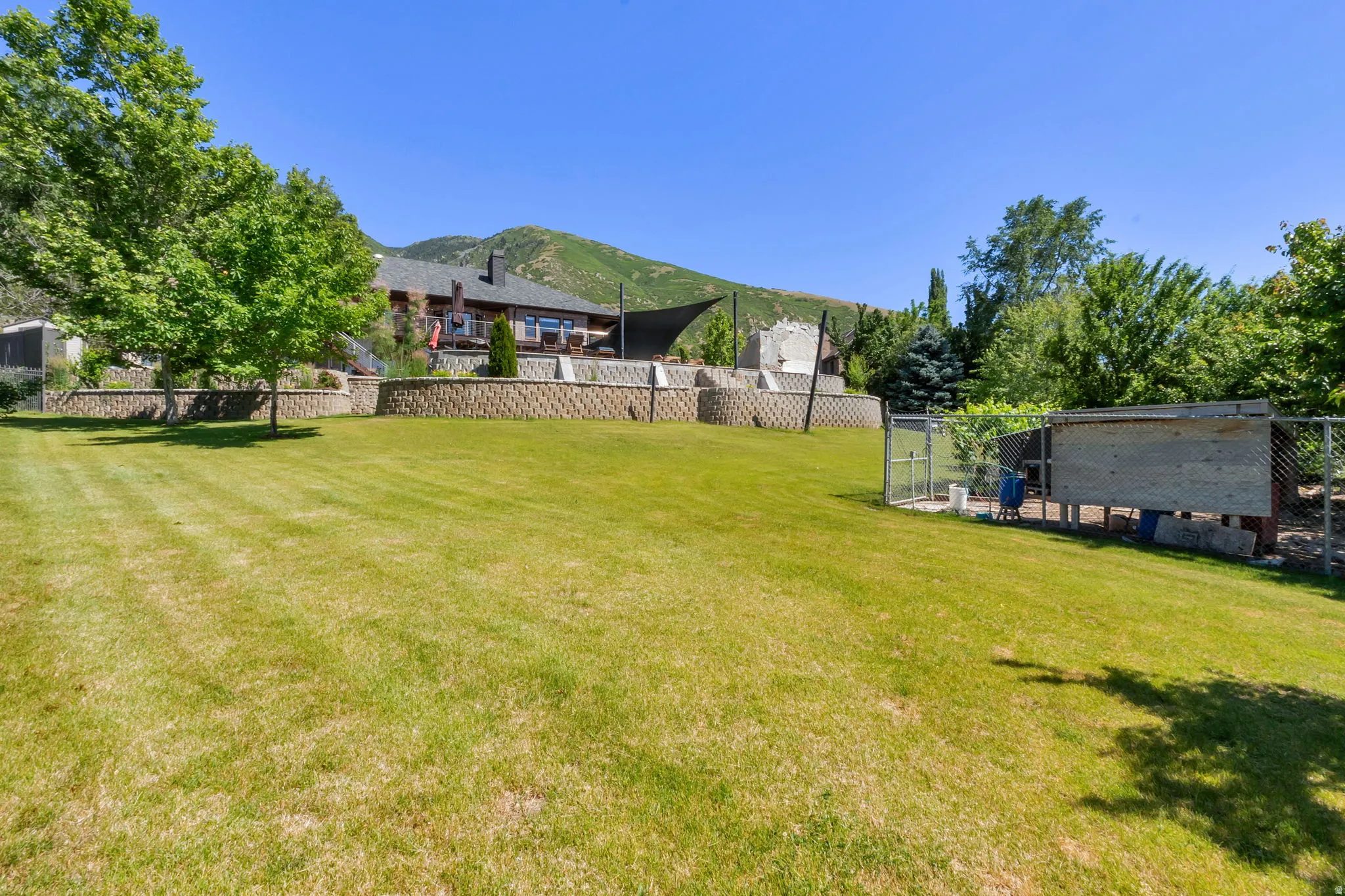 Expansive terraced yard with a large grassy area, mature trees, and a distant mountain backdrop