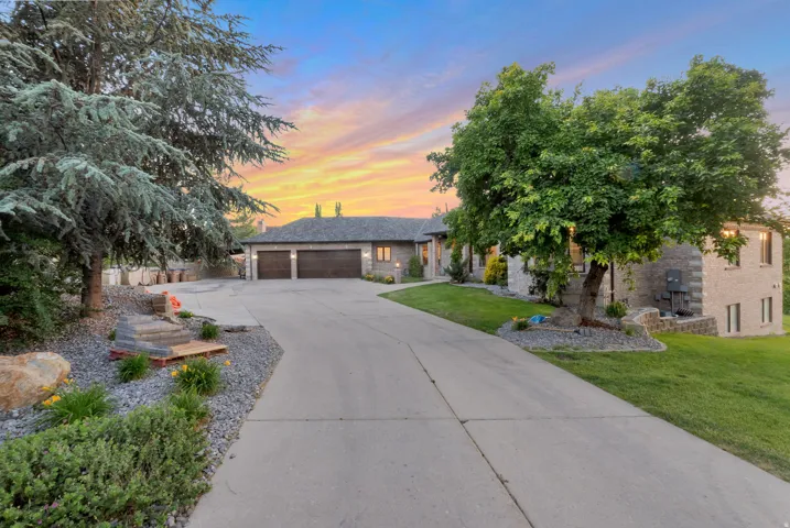 Stone-clad residence featuring a concrete driveway, three-car garage , and extensive rock landscaping