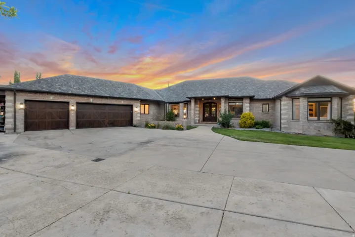 Stone facade residence featuring a multi-car garage with custom  wood-IRON doors.