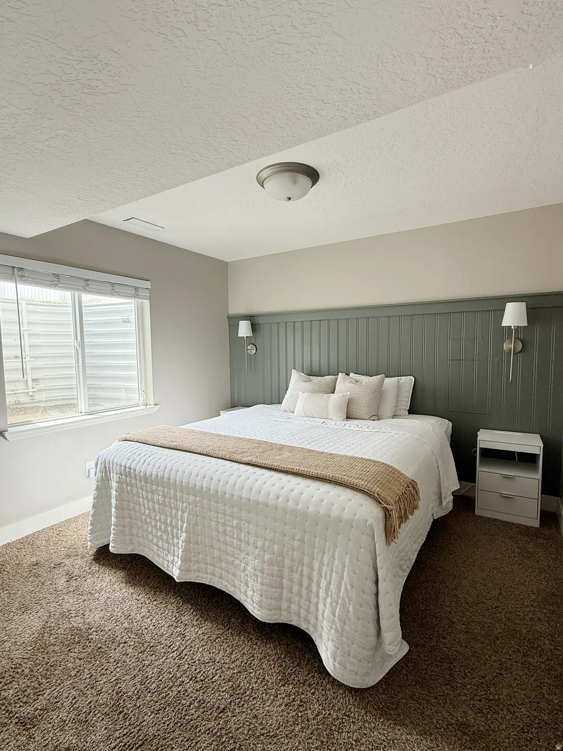 Recessed window with blinds, flanked by a paneled accent wall with integrated sconce lighting