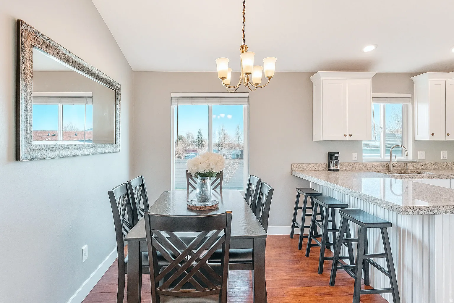 Open concept dining area featuring wood-finish flooring, a traditional chandelier, and a large window