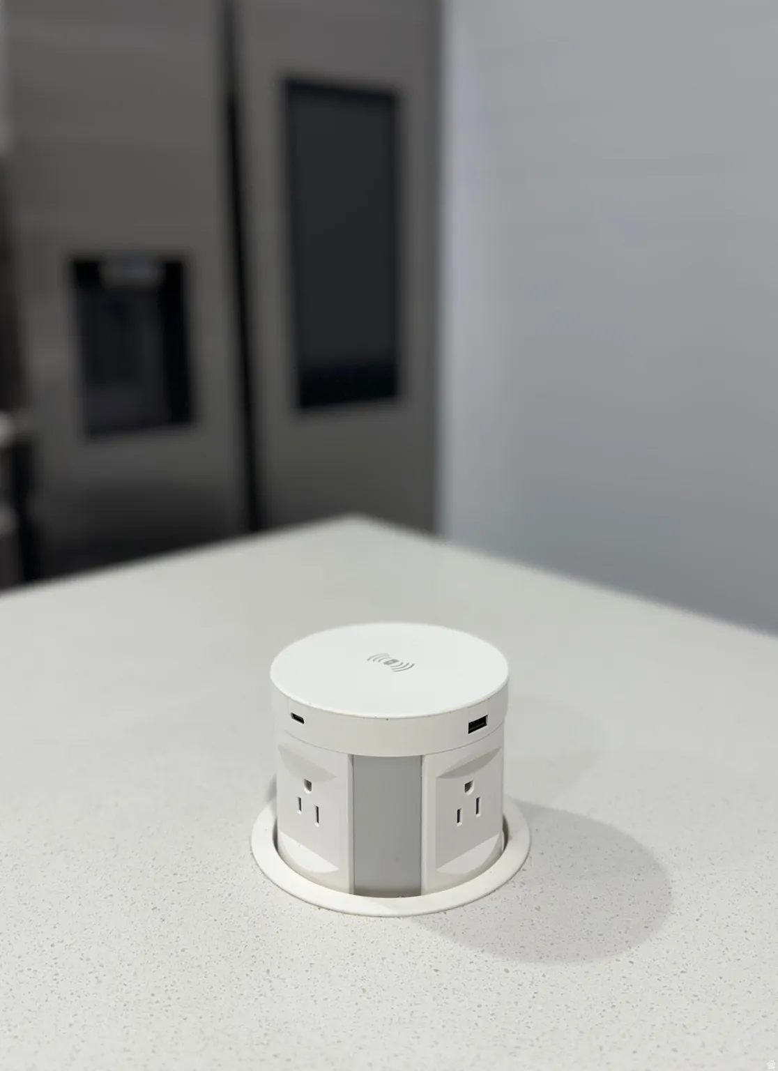 Integrated pop-up power outlet featuring multiple electrical sockets and USB ports, set within a light-colored countertop