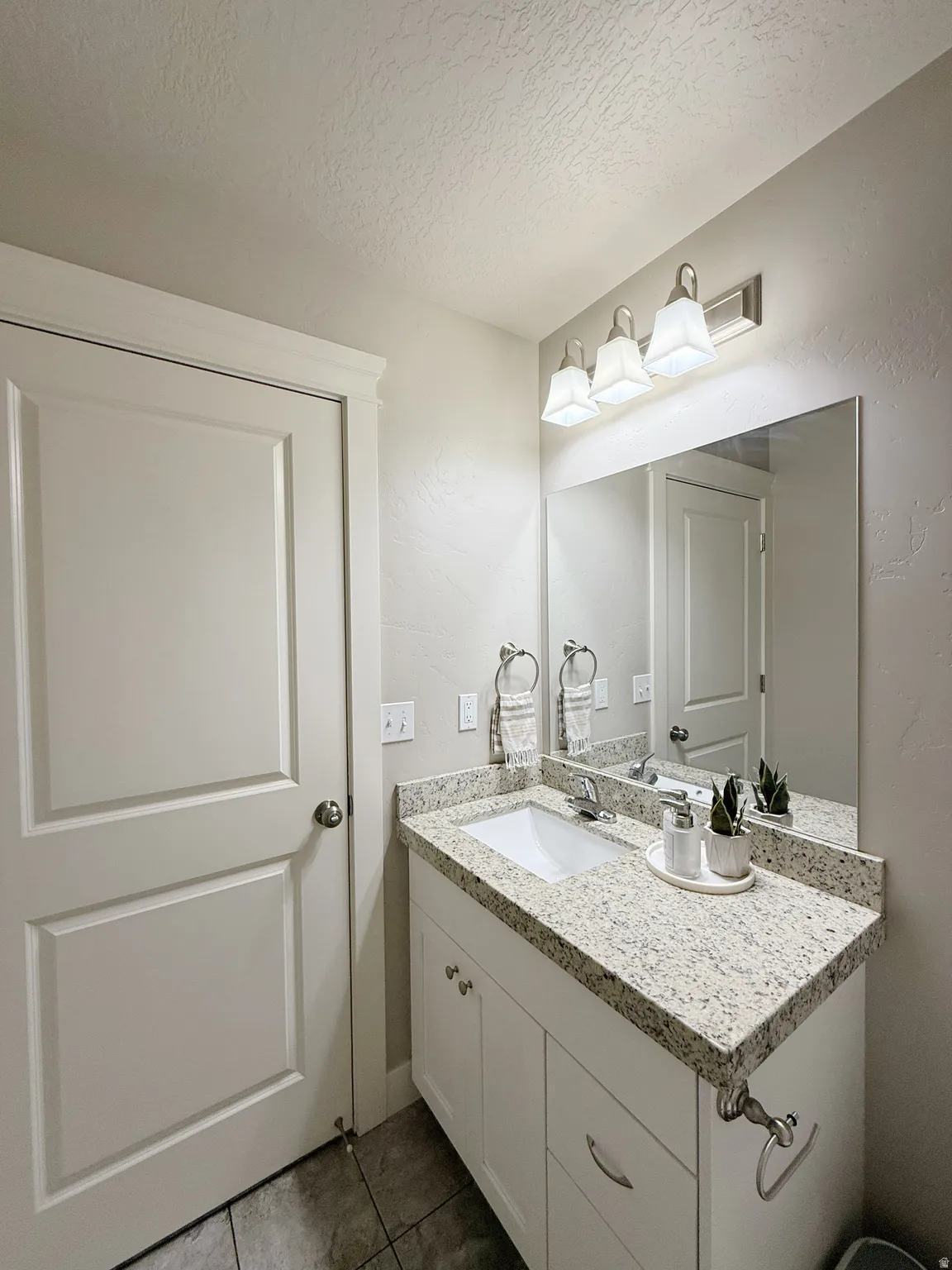 Vanity with light-toned speckled countertop, undermount sink, and brushed nickel fixtures