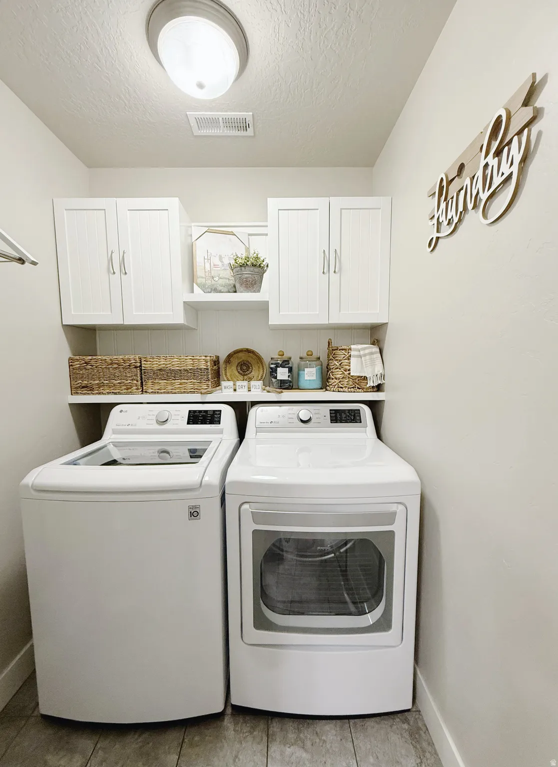 Dedicated laundry area featuring overhead cabinetry, a built-in shelving unit, and wood-finish flooring