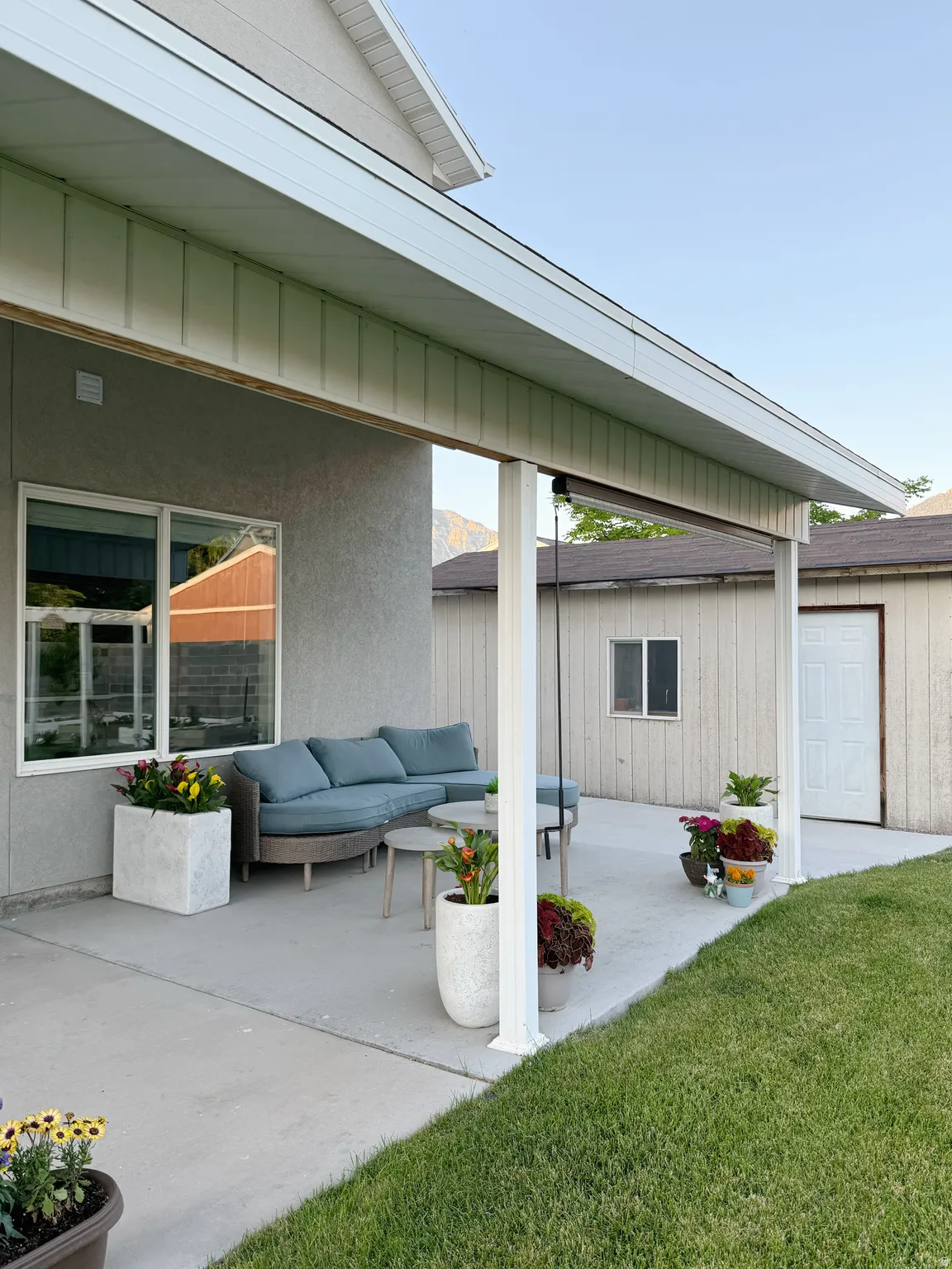 Covered patio area with a concrete surface, white support columns, and a stucco exterior wall