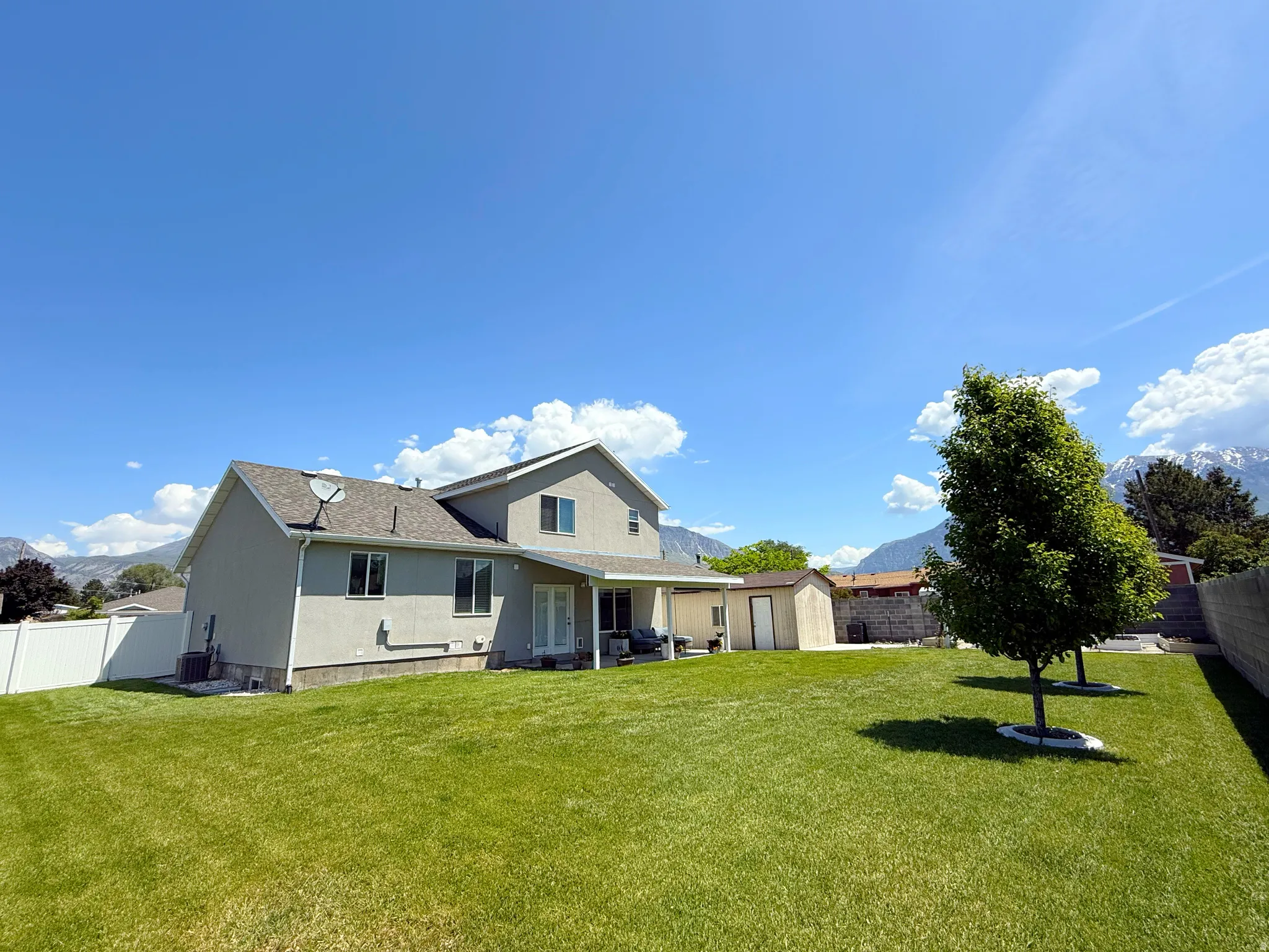Expansive green lawn with mature trees and a fenced perimeter