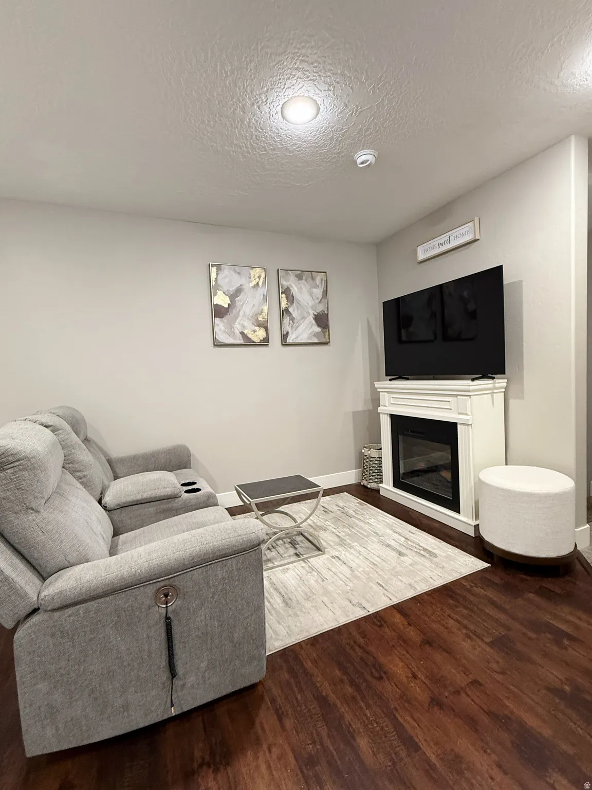 Spacious living area featuring wood-finish flooring, recessed lighting, and a white mantel with an electric fireplace