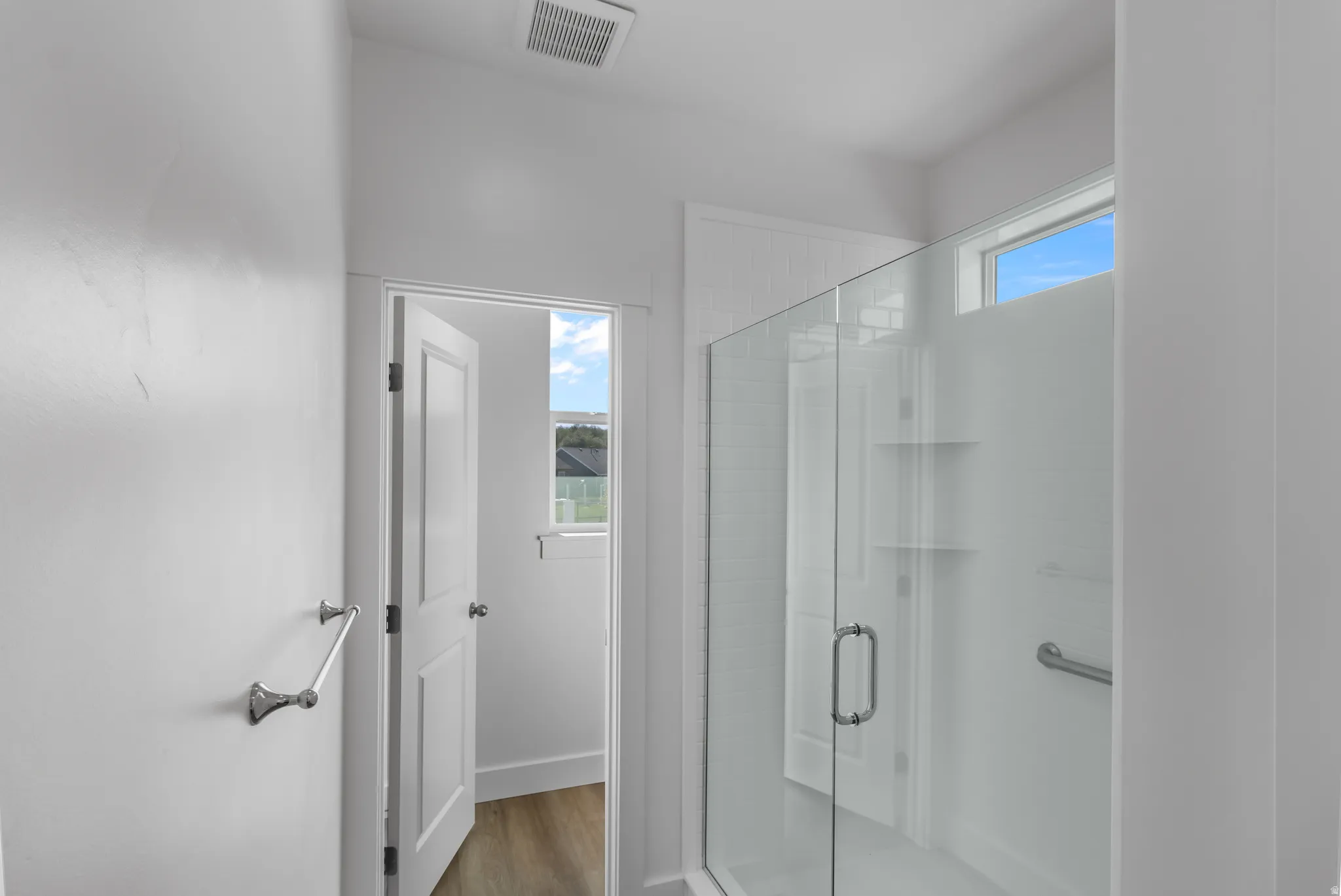 Glass-enclosed shower with white subway tile, built-in shelving, and a chrome grab bar