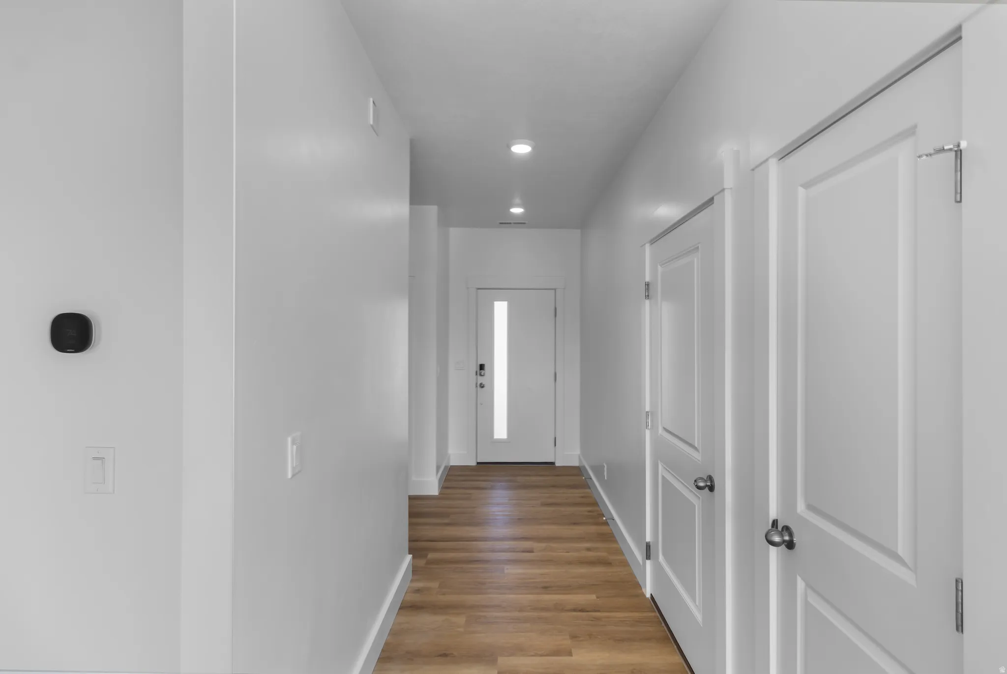 Entryway featuring wood-finish flooring, recessed lighting, and a modern white front door with frosted glass