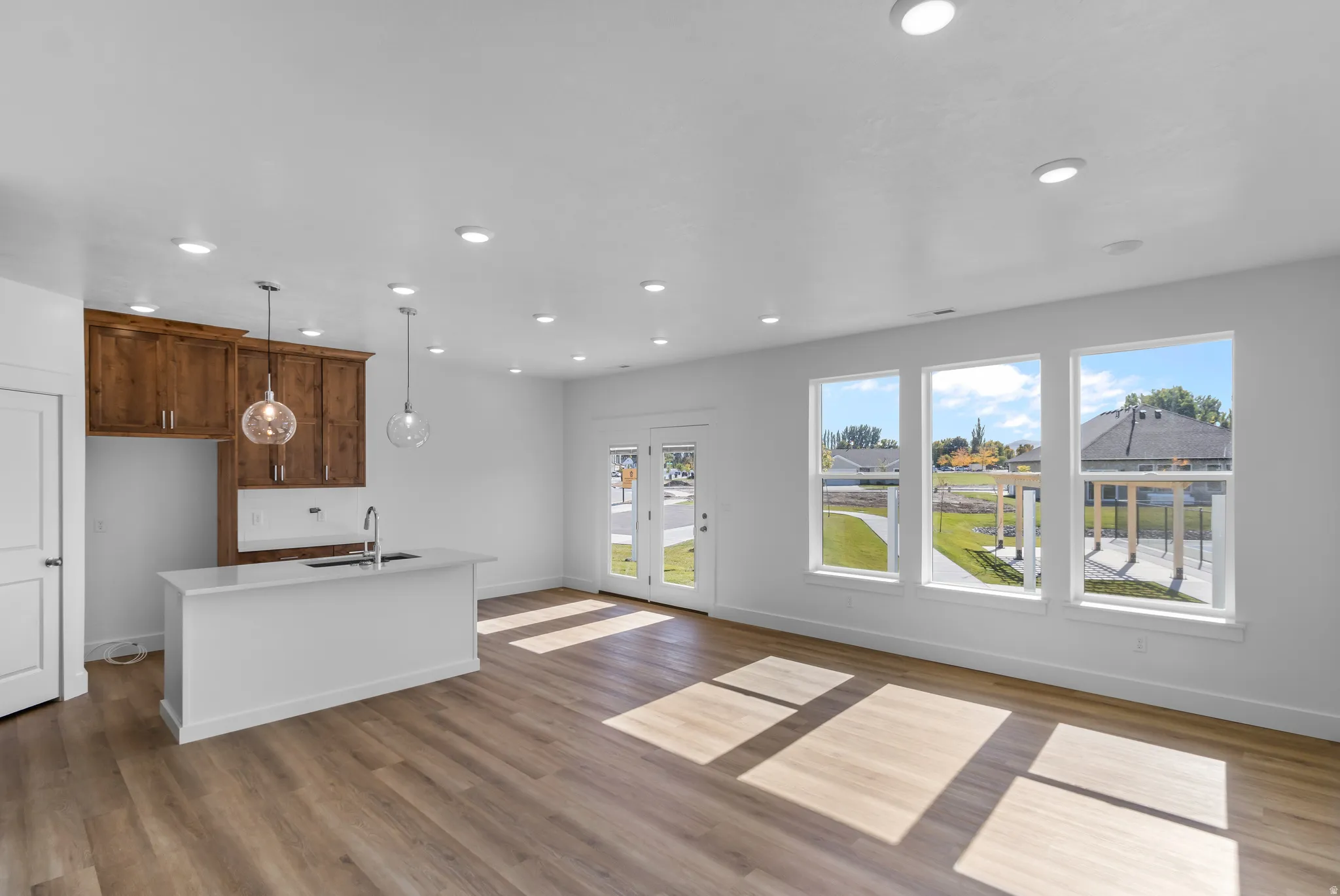 Open-concept living area featuring wood-finish flooring, recessed lighting, and a kitchen island with an undermount sink