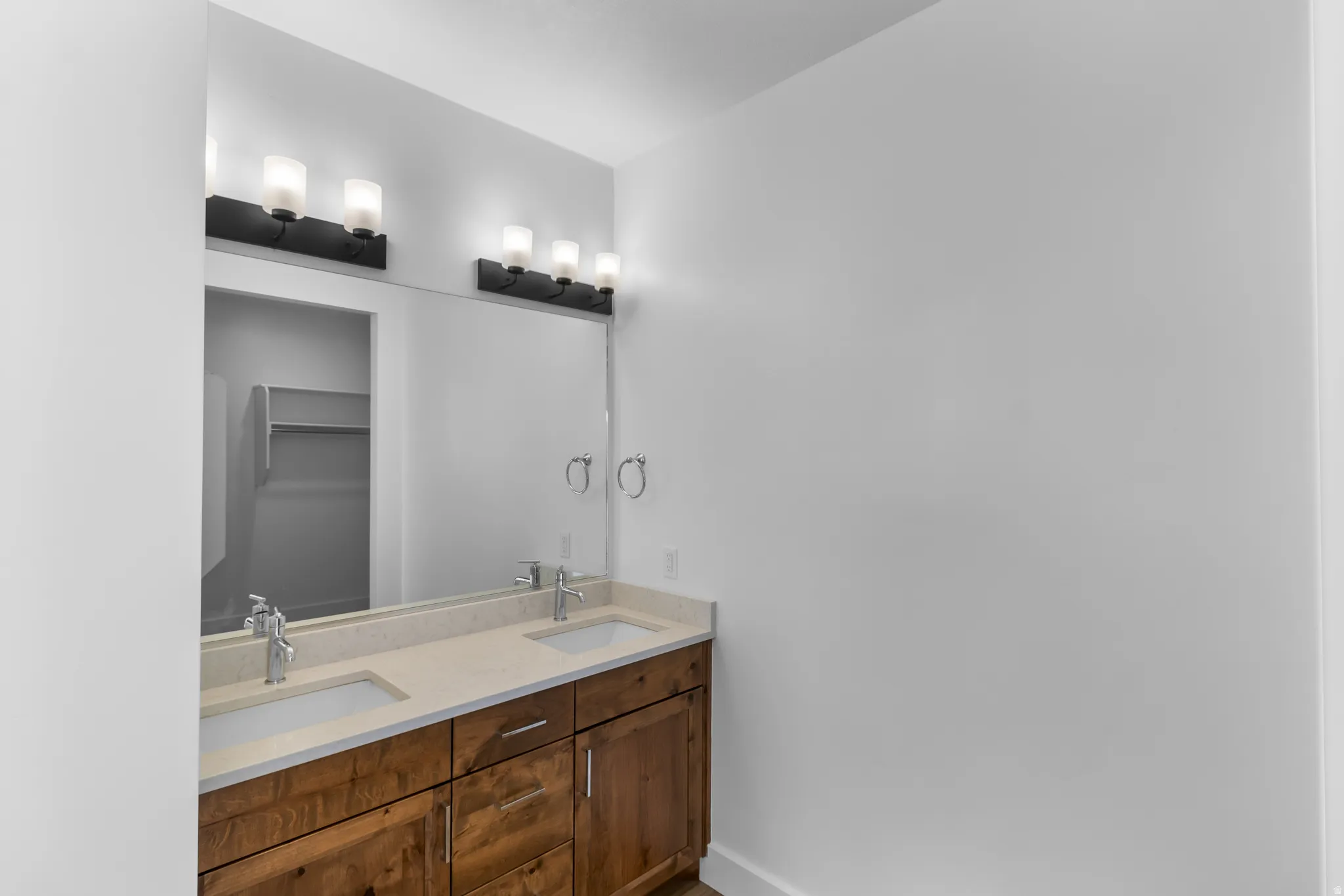 Dual vanity with wood-finish cabinetry, light-toned countertops, and two undermount sinks