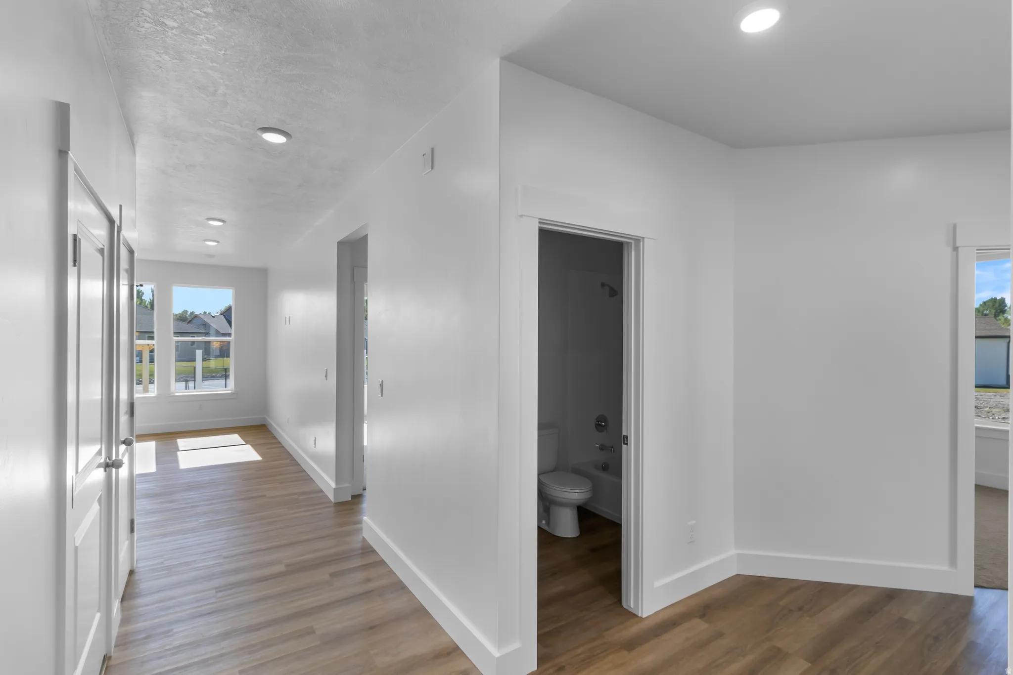 Corridor featuring wood-finish flooring, recessed lighting, and white baseboards