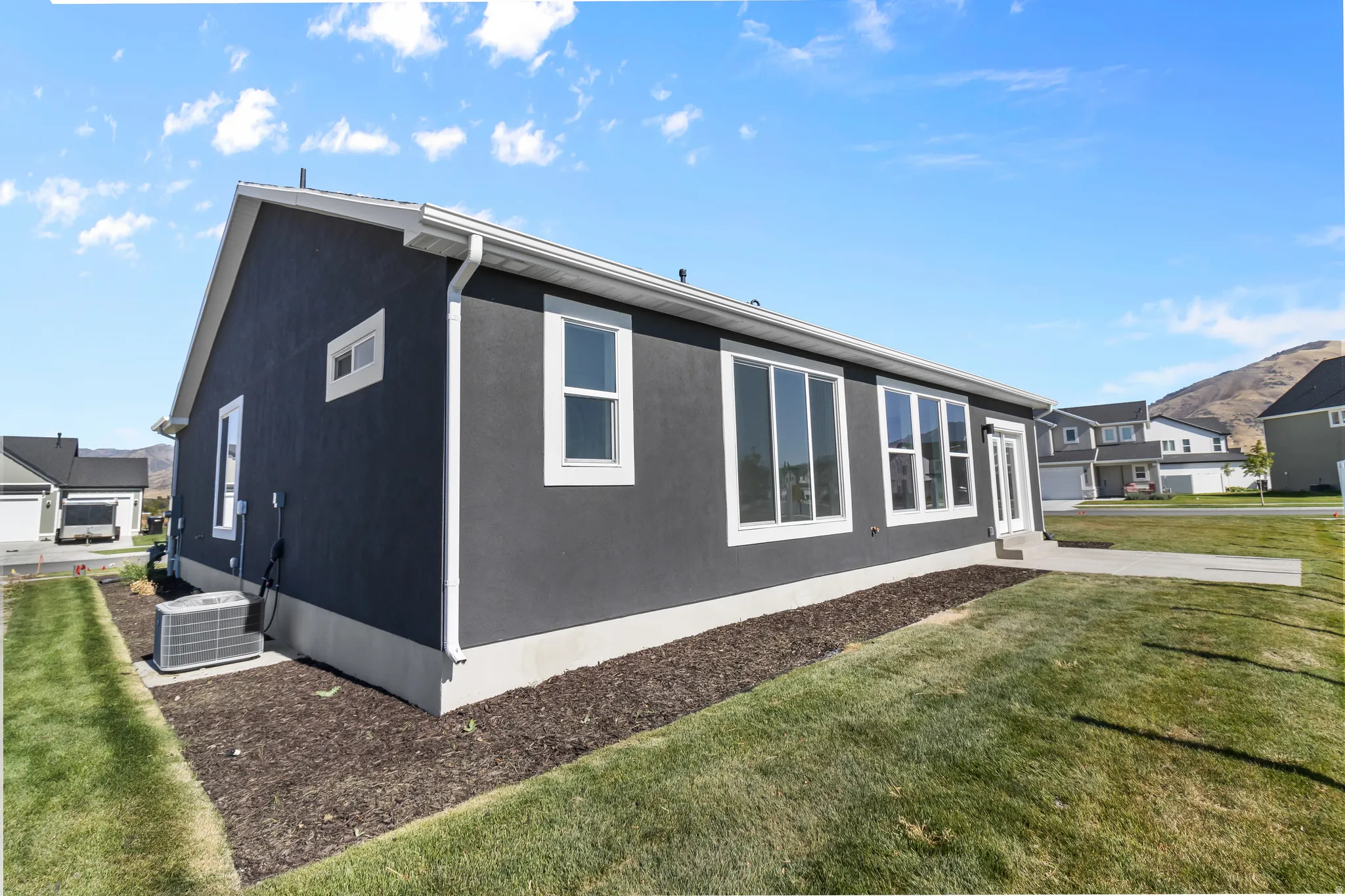 Contemporary single-story residence with dark stucco siding and white trim