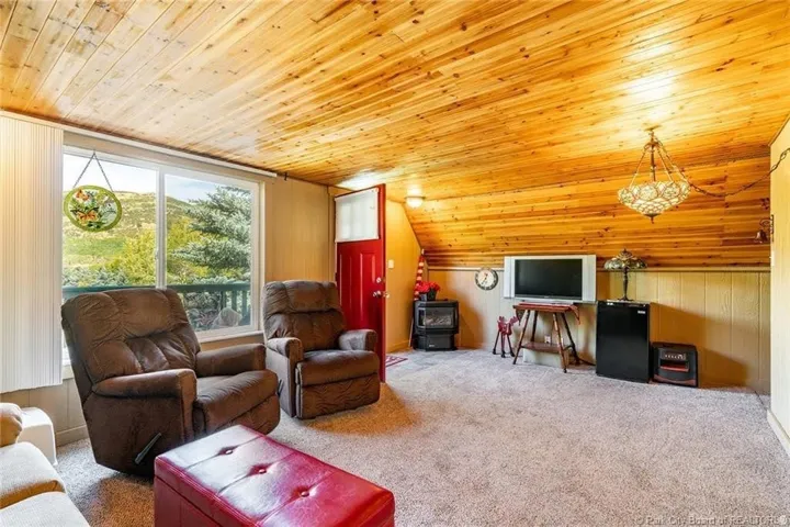 Room featuring a wood-panel ceiling, light-colored carpet, and a large window offering expansive scenery