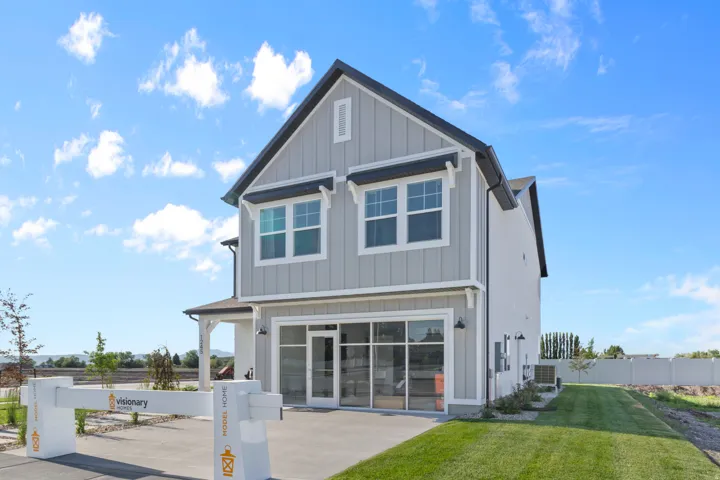Modern farmhouse exterior featuring light gray vertical siding, dark trim accents, a prominent gable, and a two-car garage with a large glass door