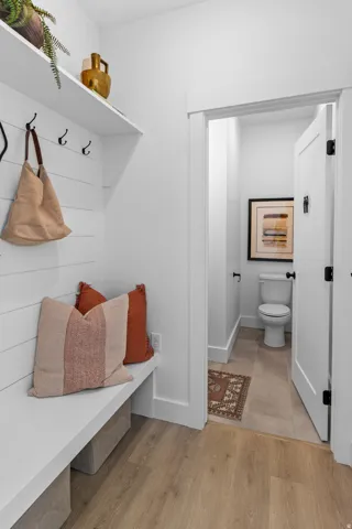 Entryway featuring built-in bench seating, upper shelving, and wall-mounted hooks
