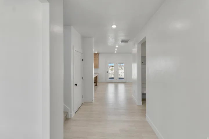 Long hallway featuring light wood-finish flooring and recessed lighting