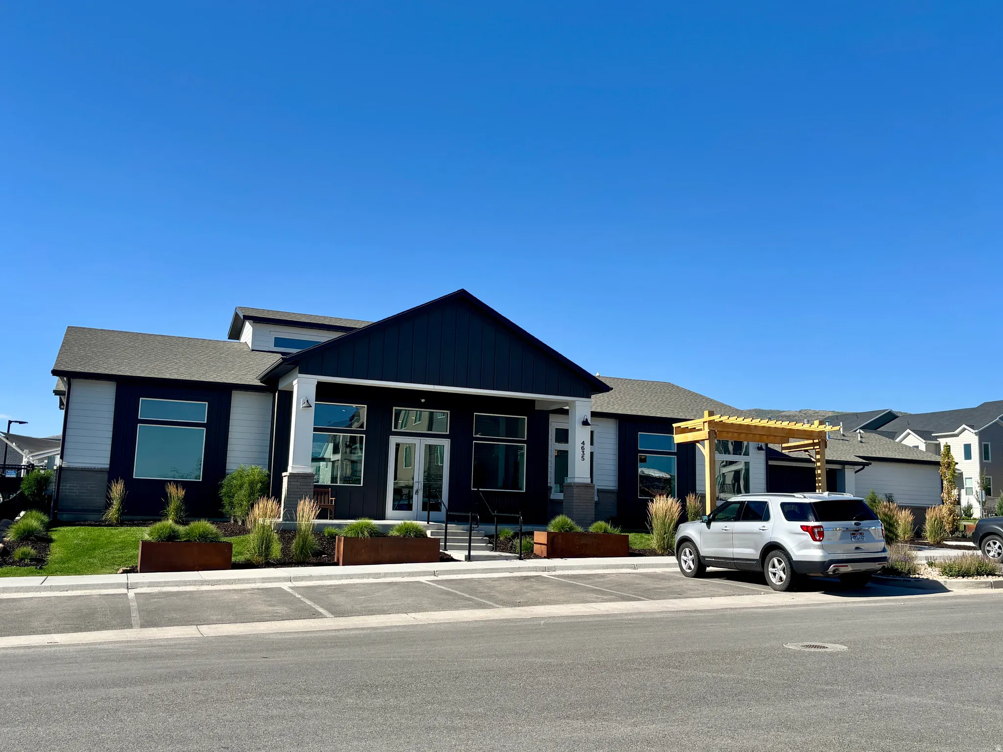 CLUBHOUSE EXTERIOR Contemporary exterior featuring dark siding, white trim, and a prominent gable entry