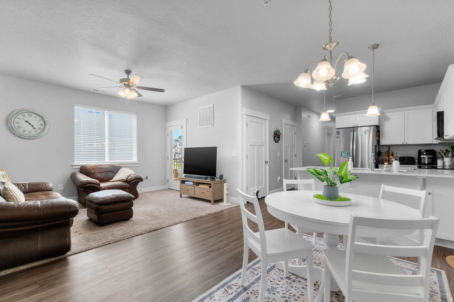 Open-concept living area with wood-finish flooring, a ceiling fan, and a light-filled window