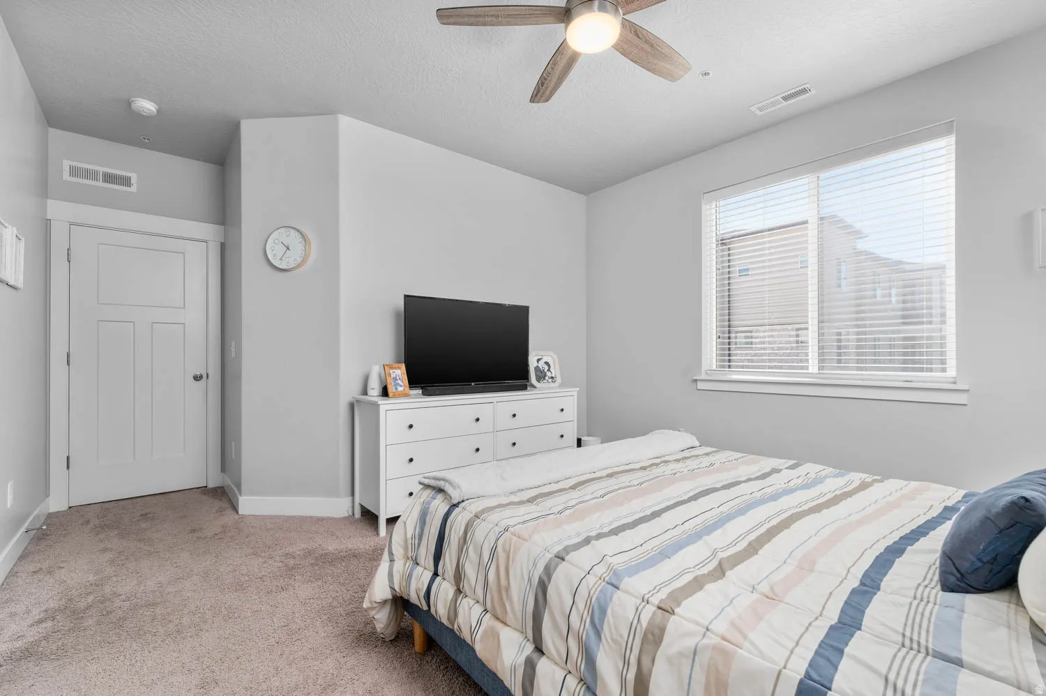 Carpeted bedroom featuring a ceiling fan with integrated lighting, a rectangular window with blinds, and white trim molding