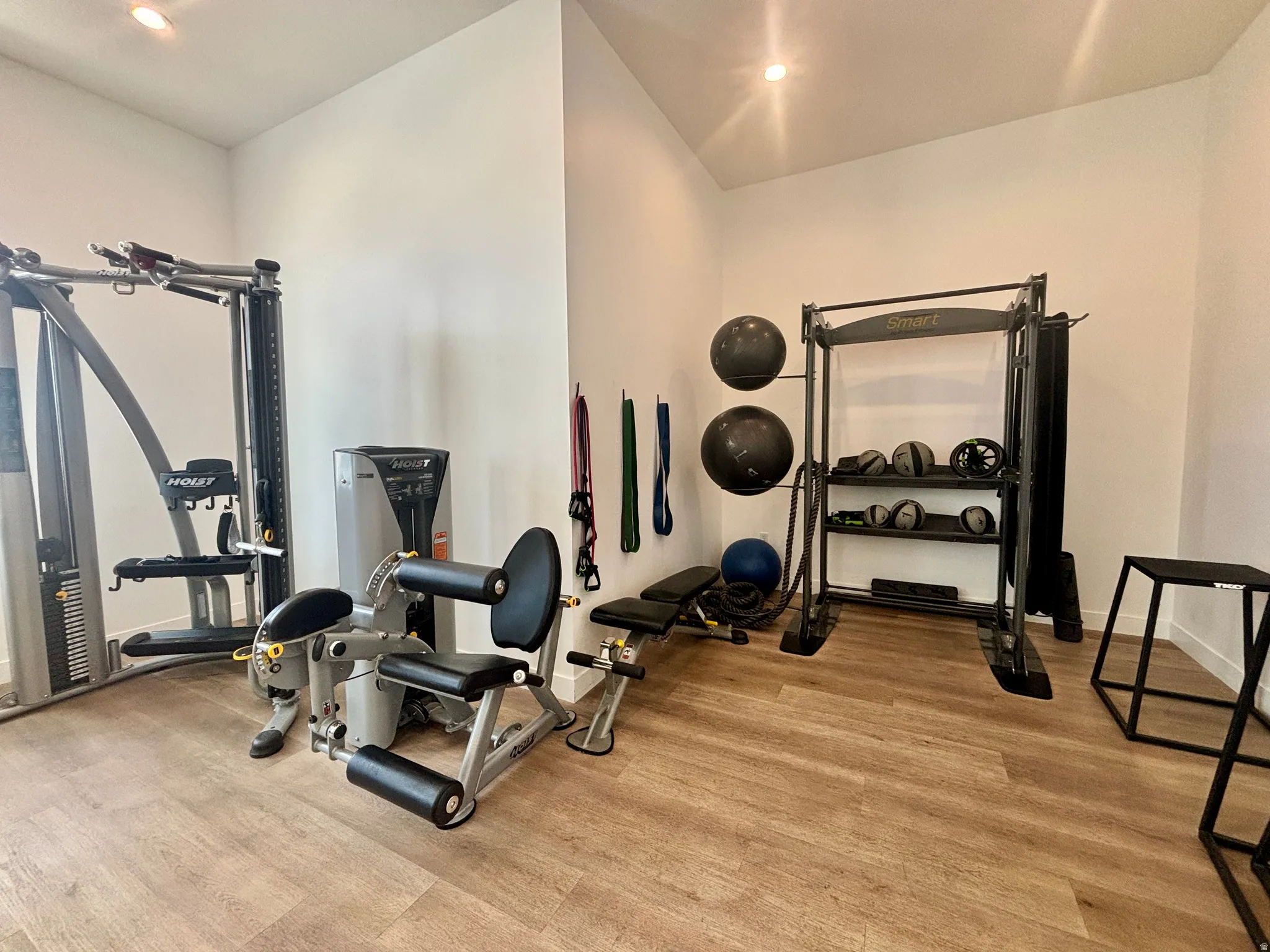 Dedicated fitness room featuring wood-finish flooring, recessed lighting, and bright white walls