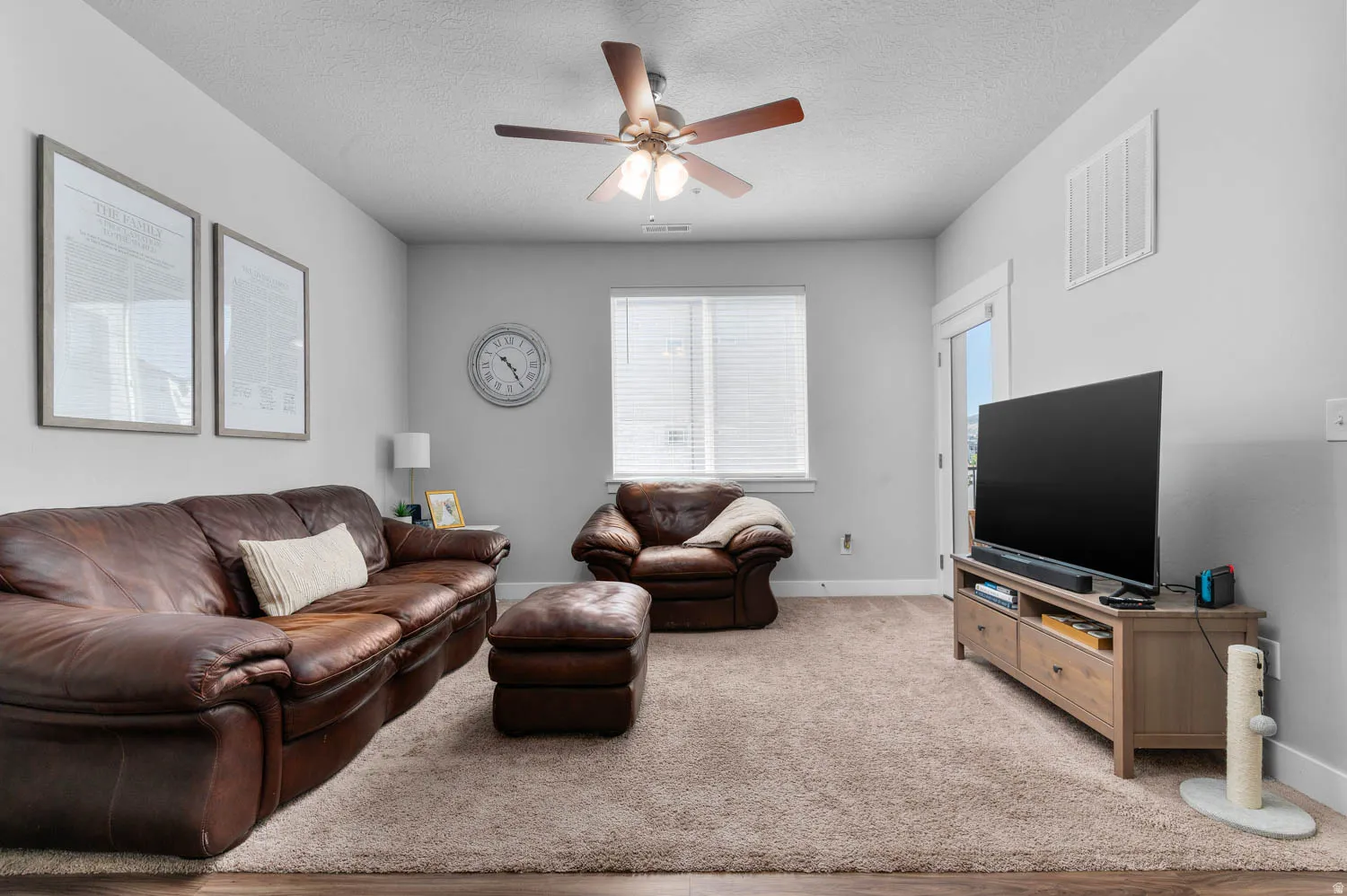 Open living area featuring neutral wall tones and a ceiling fan with integrated lighting