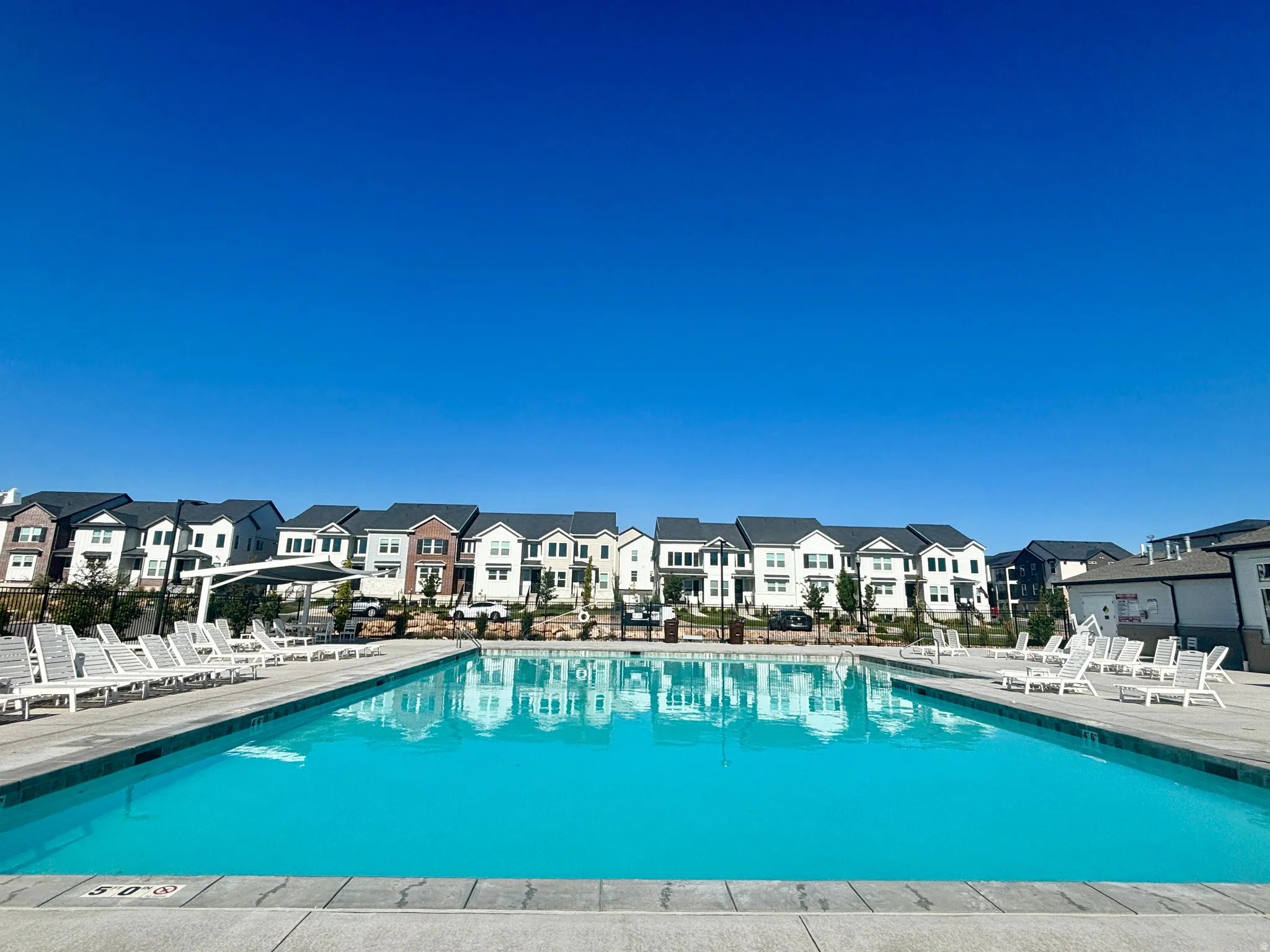 Community swimming pool featuring a concrete deck and multiple lounge chairs